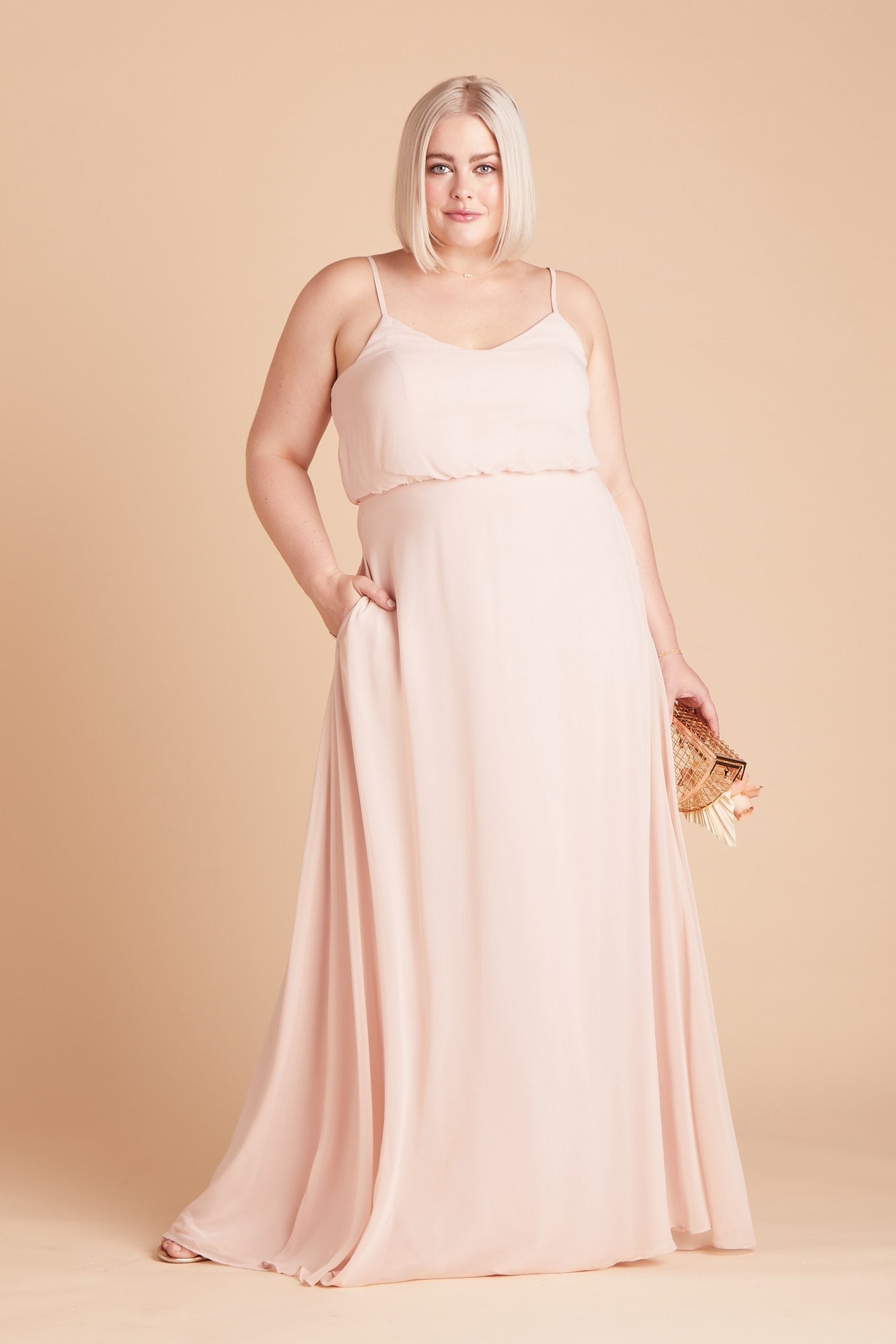 Gwennie plus size bridesmaid dress in pale blush chiffon by Birdy Grey, front view with hand in pocket