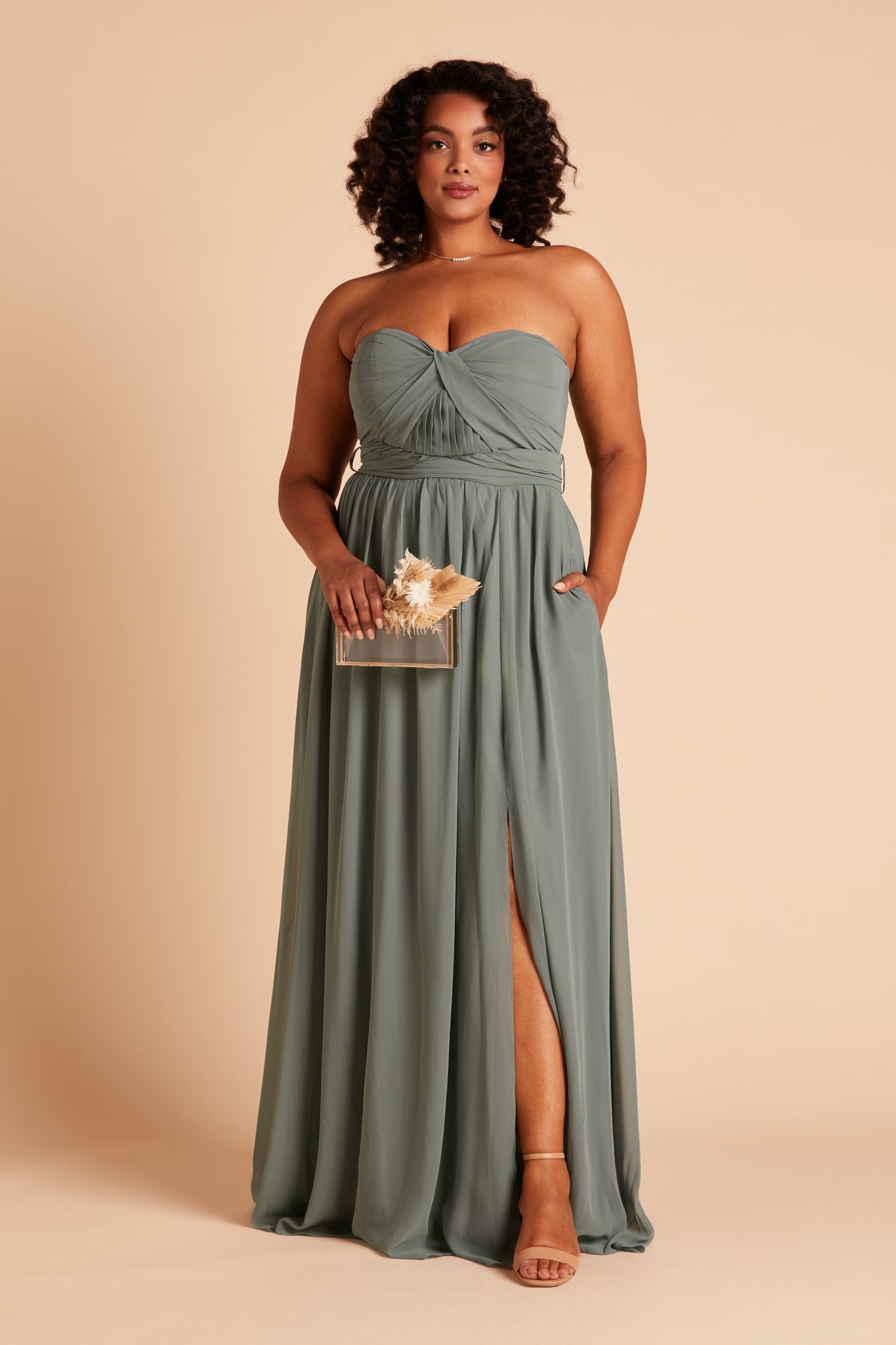 Front view of the Grace Convertible Plus Size Dress in sea glass chiffon as the model rests her left hand in the hidden side pocket.