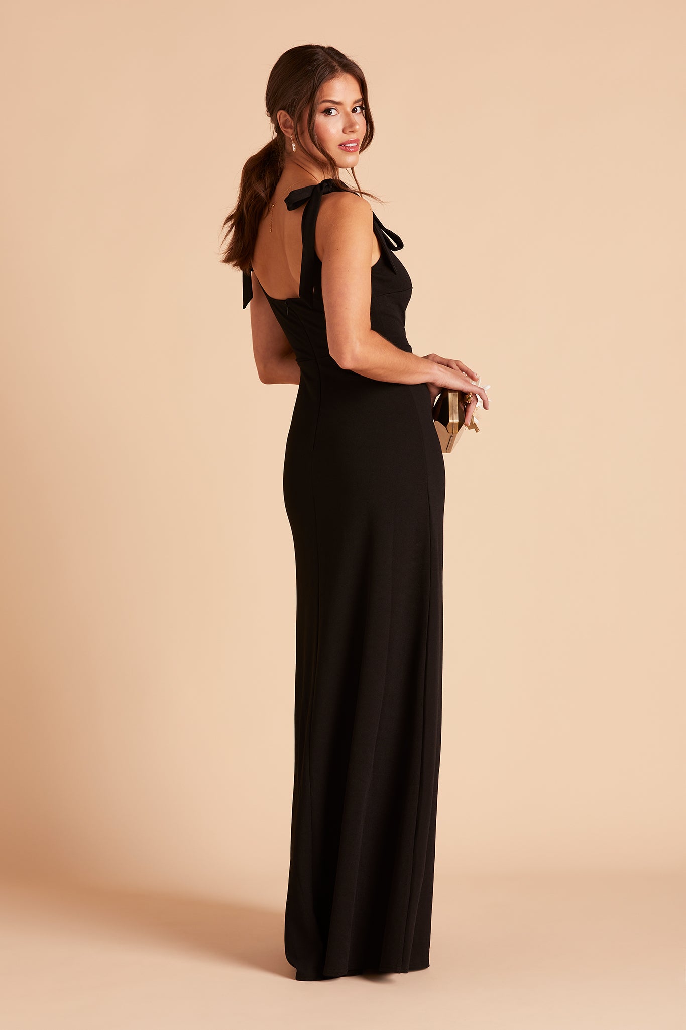 Side view of the Alex Convertible Bridesmaid Dress in black crepe with shoulder ties reveals a slender silhouette with the skirt flowing delicately from the waistline to the floor.