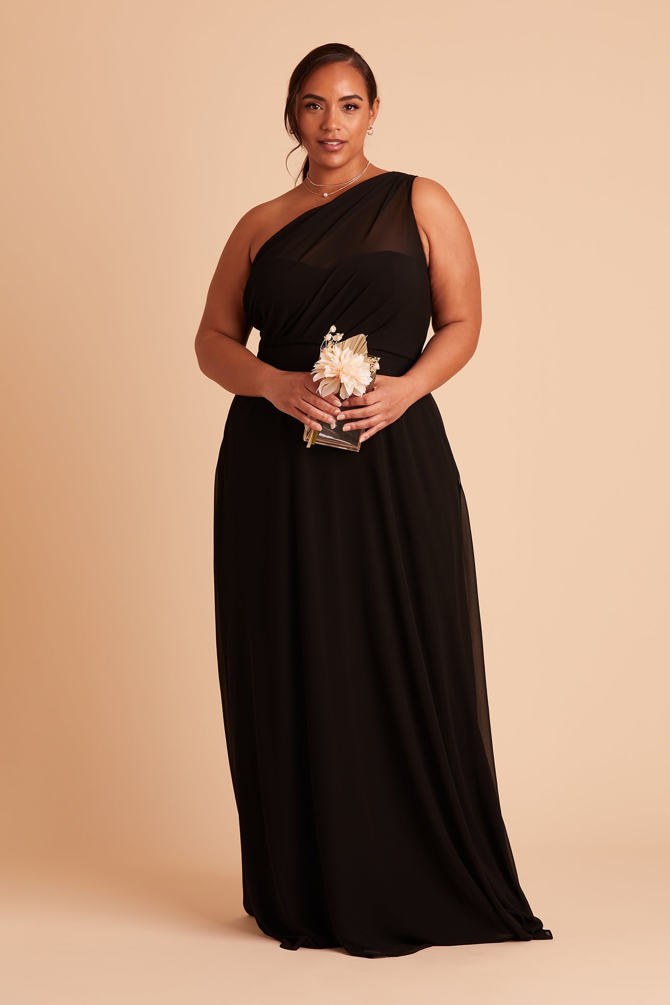 Front view of the Kira Dress Curve in black chiffon without the optional slit shows a full-figured model with a medium skin tone holding the Clear Clutch with Clear Beads purse.