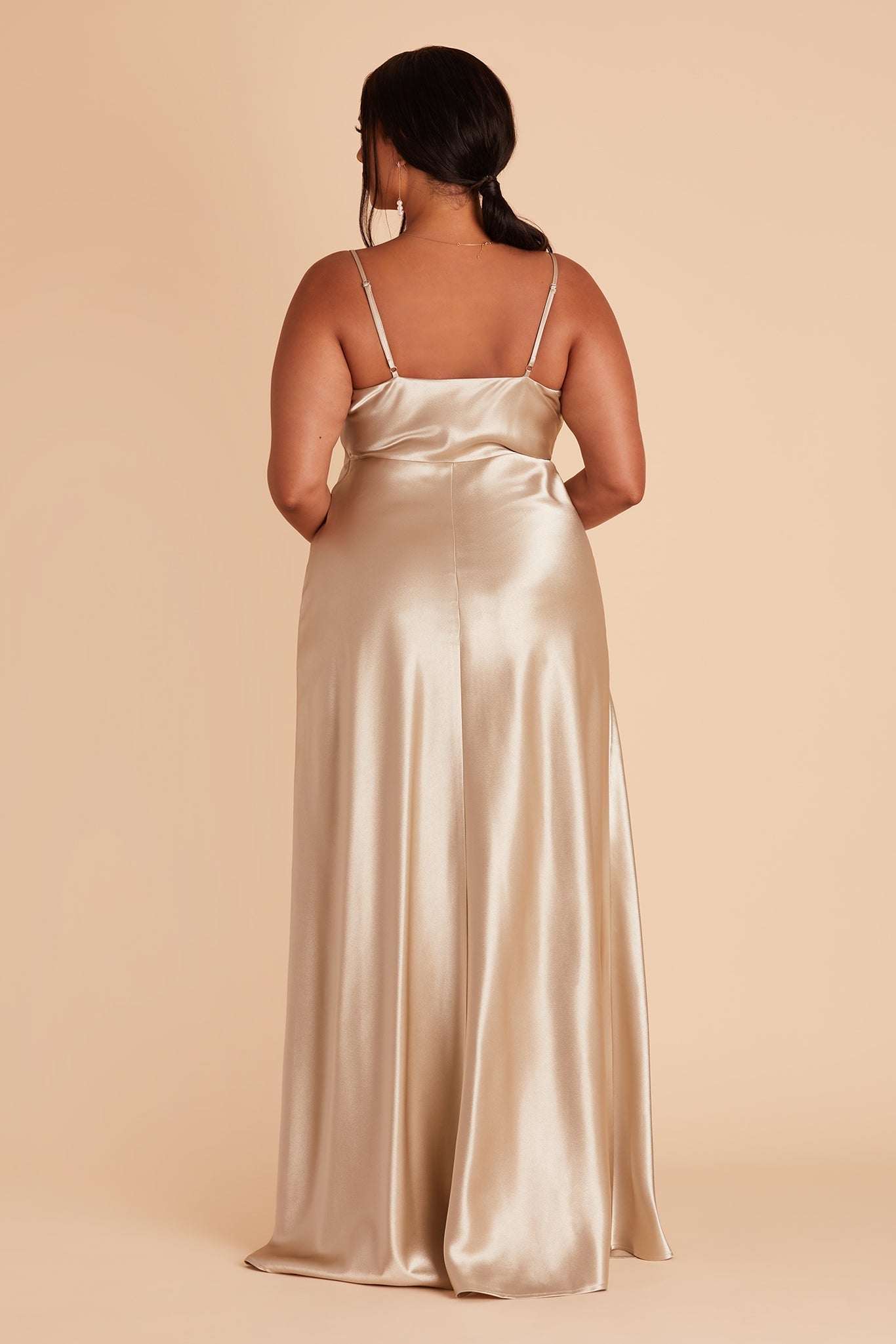 Back view of the Lisa Long Dress Curve in neutral champagne satin shows the back of the dress with adjustable spaghetti straps and a smooth fit in the bodice and waist that attach to a full length skirt.  