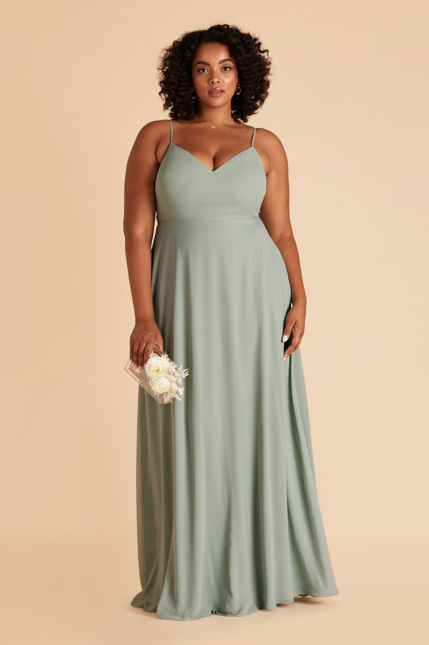 Front view of the floor-length Devin Convertible Plus Size Bridesmaid Dress in sage chiffon with a V-neck front and simple spaghetti straps. The flowing skirt has no slit, as this is an optional feature.