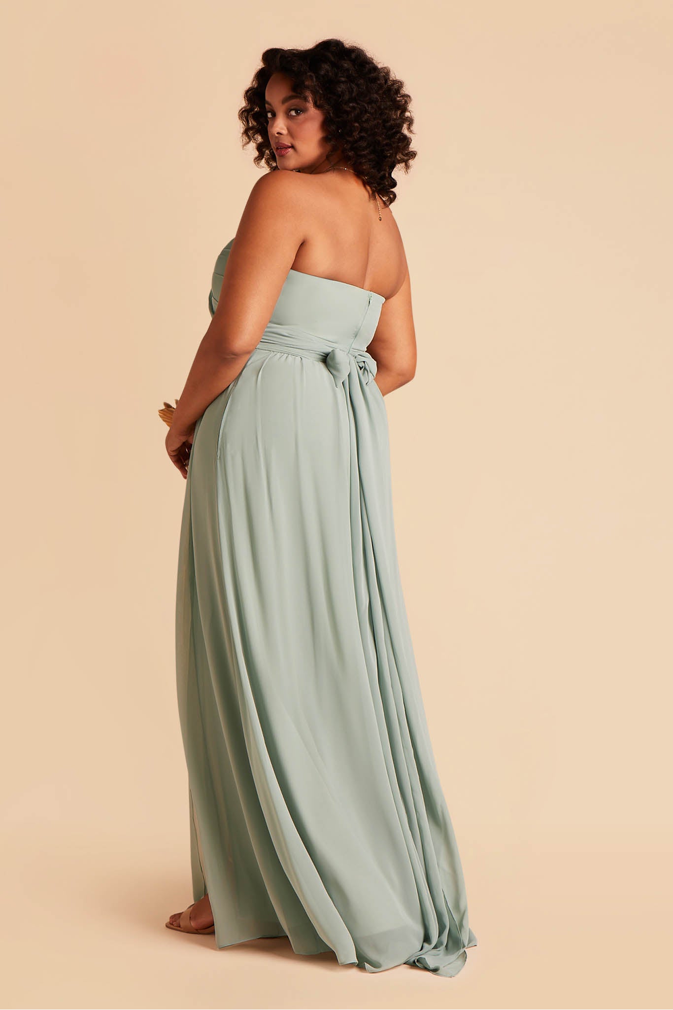 Side view of the Grace Convertible Plus Size Bridesmaid Dress in sea glass chiffon reveals a fitted bust with a floor-length skirt flowing from the waist.