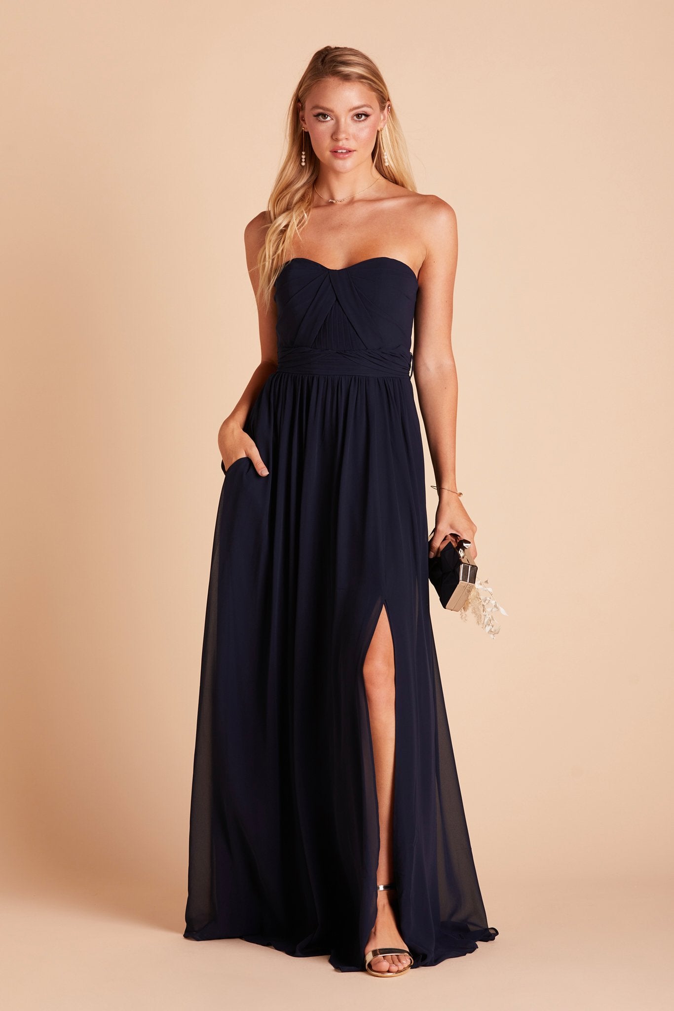 Grace convertible bridesmaid dress in navy blue chiffon with slit by Birdy Grey, front view with hand in pocket
