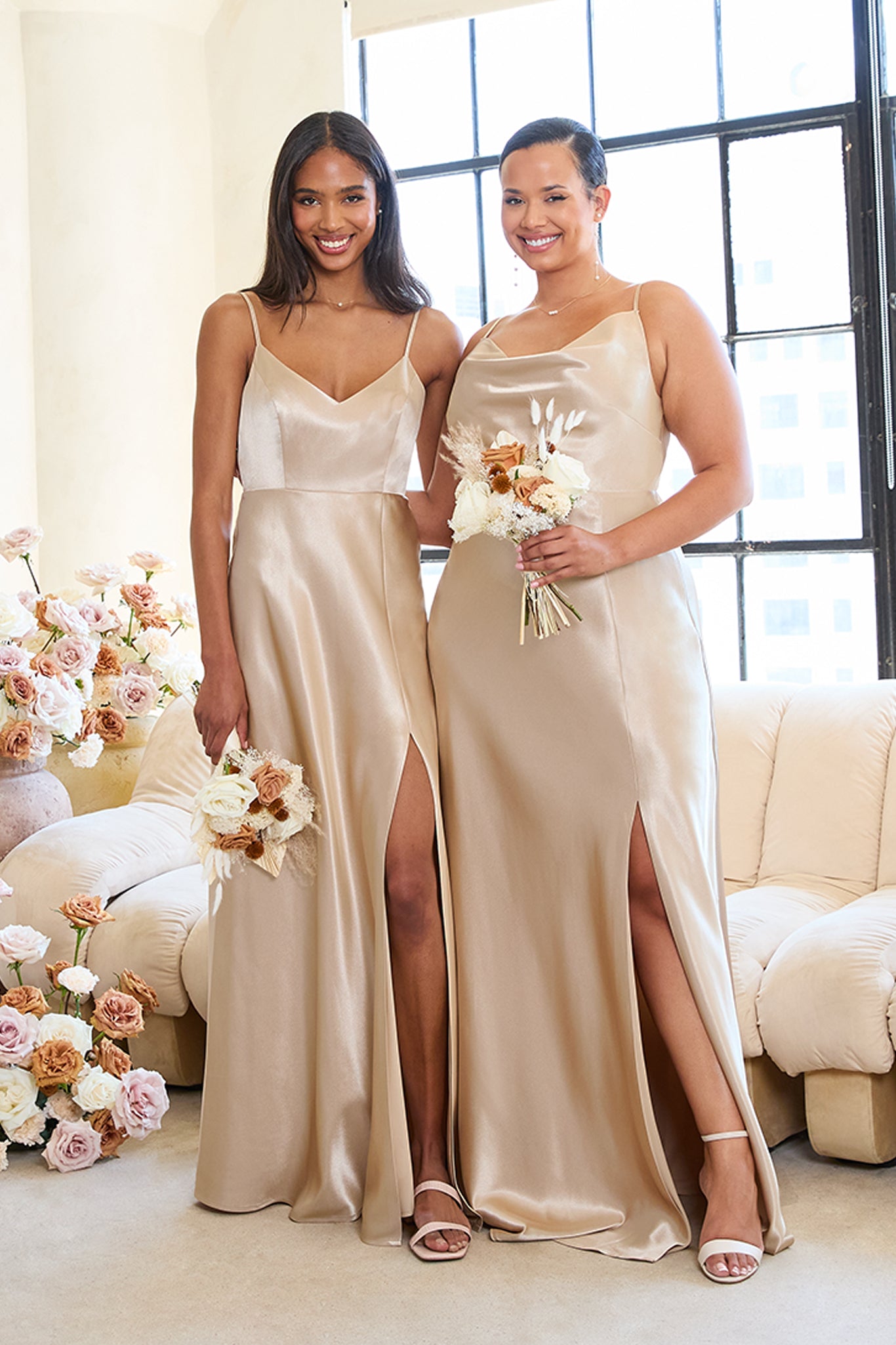 Front view of two models with their arms around each other wearing Birdy Grey Bridesmaid Dresses in neutral champagne. On the left, a slender model with a medium skin tone wears the Jay Bridesmaid Dress. On the right, a curvy model with a light skin tone wears the Lisa Long Plus Size Bridesmaid Dress.