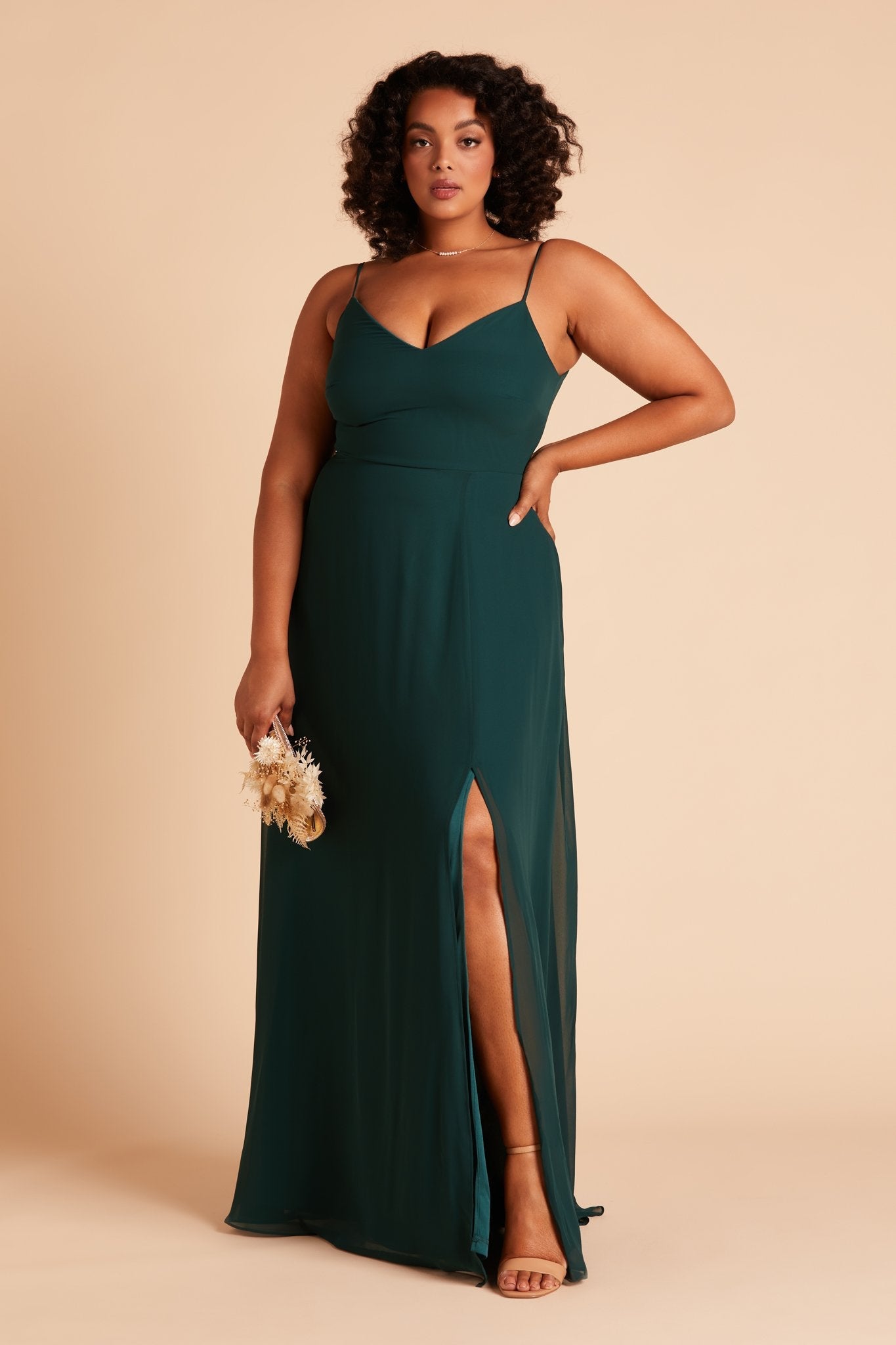 Front view of the floor-length Devin Convertible Plus Size Bridesmaid Dress in emerald chiffon worn by a curvy model with a medium skin tone.