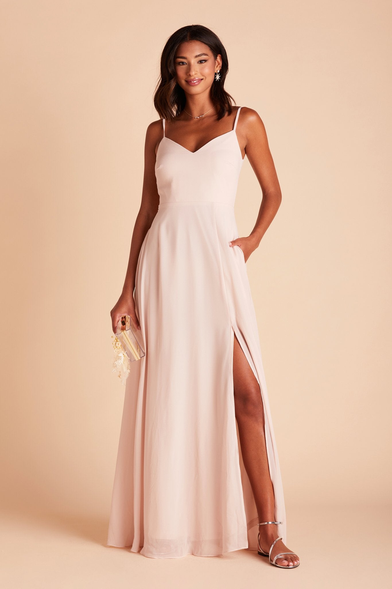 Devin convertible bridesmaids dress with slit in pale blush chiffon by Birdy Grey, front view with hand in pocket