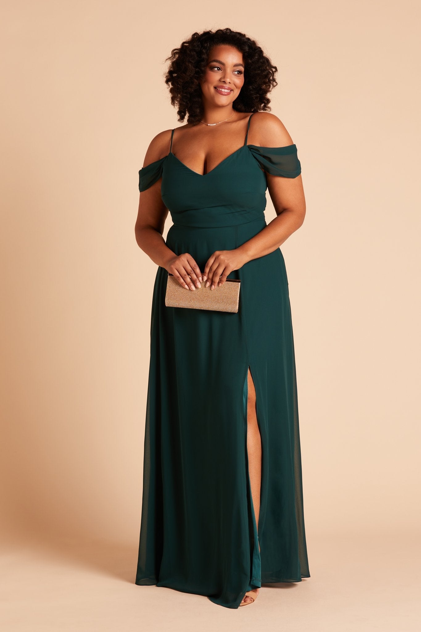 Front view of the floor-length Devin Convertible Plus Size Bridesmaid Dress in emerald chiffon by Birdy Grey with a V-neck front and draping detachable sleeves. The flowing skirt features a slit over the left leg.