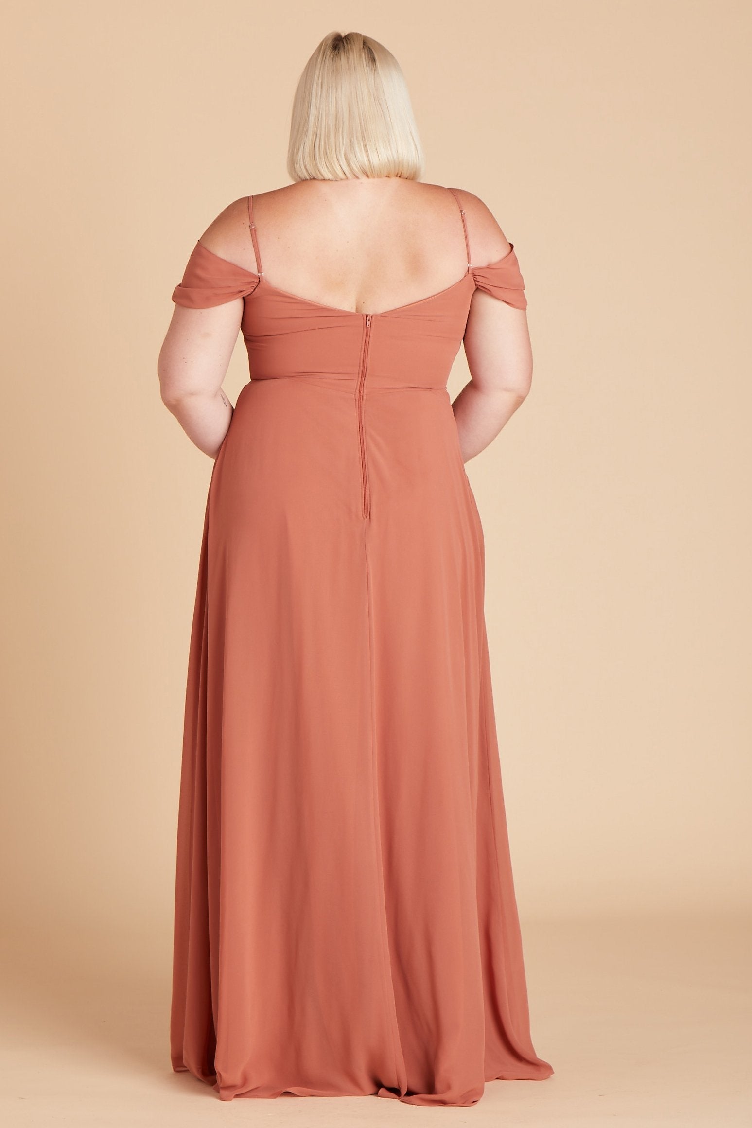 Back view of the floor-length Devin Convertible Plus Size Bridesmaid Dress in terracotta chiffon features a fitted bust and waist with a flowing skirt that moves with the model.