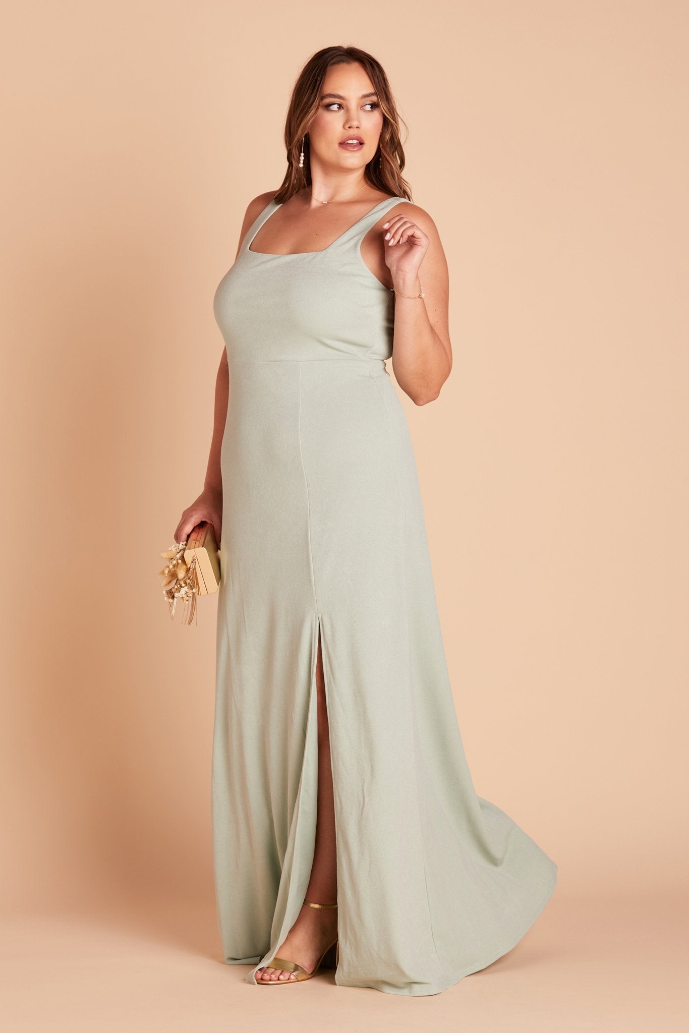 Side view of the Alex Convertible Plus Size Bridesmaid Dress in sage green crepe without shoulder ties reveals a fitted bust and waistline with a delicate flowing floor-length skirt.