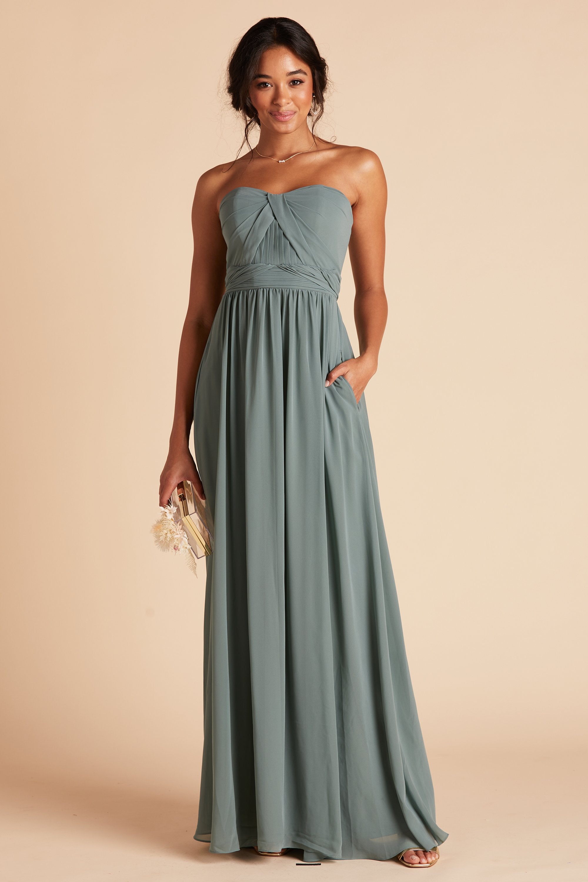 Front view of the floor-length Grace Convertible Bridesmaid Dress in sea glass chiffon as the model rests her left hand in the hidden side pocket.