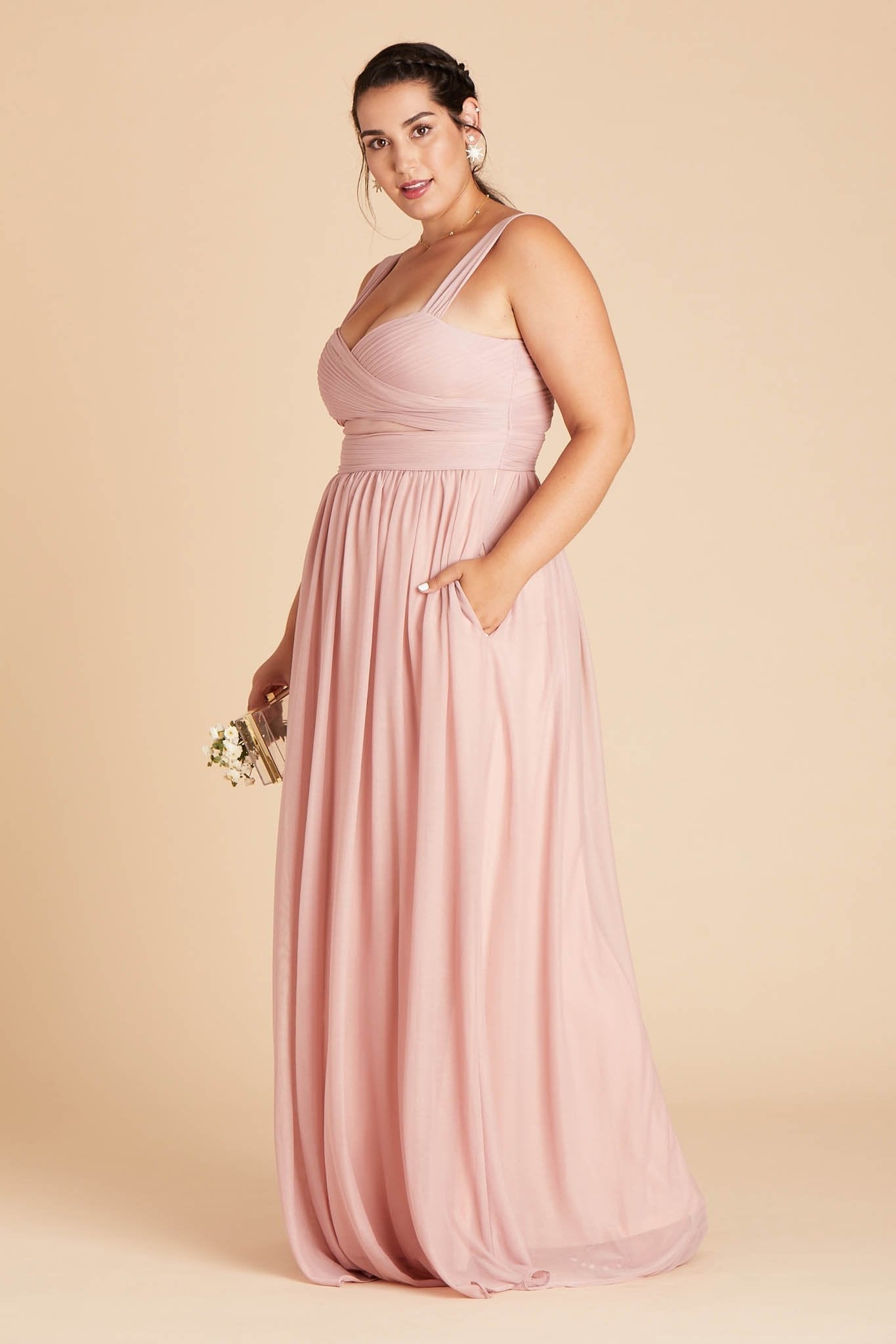 Front view of the Elsye Plus Size Bridesmaid Dress in dusty rose as the model rests her left hand in the hidden side pocket.