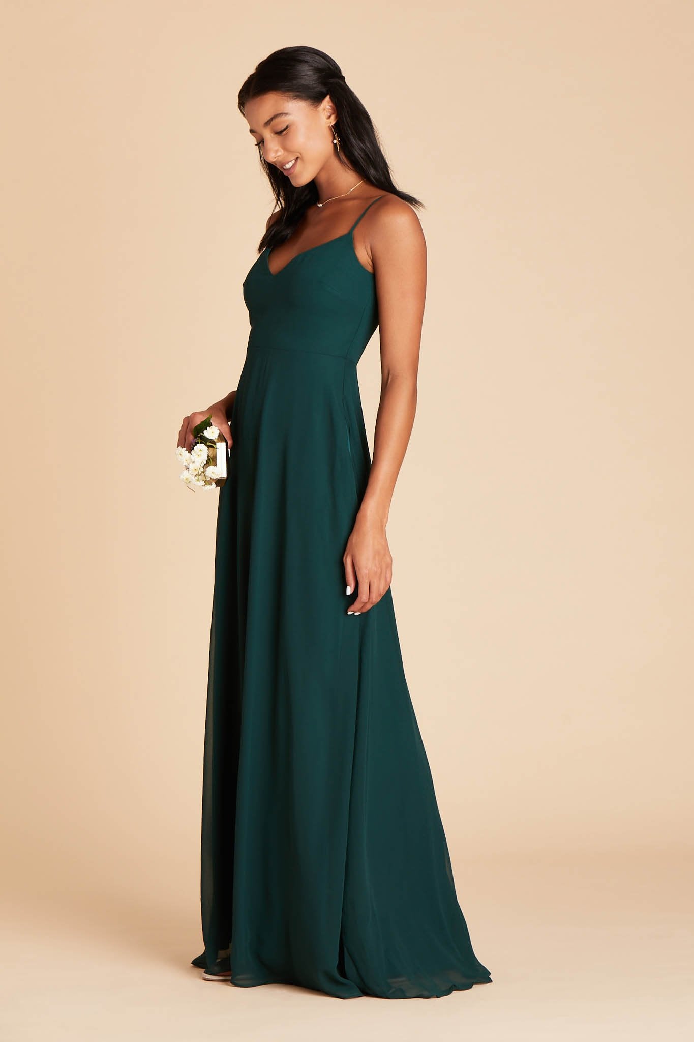 Side view of the floor-length Devin Convertible Bridesmaid Dress in emerald chiffon reveals a fitted bust and flowing full-length skirt.