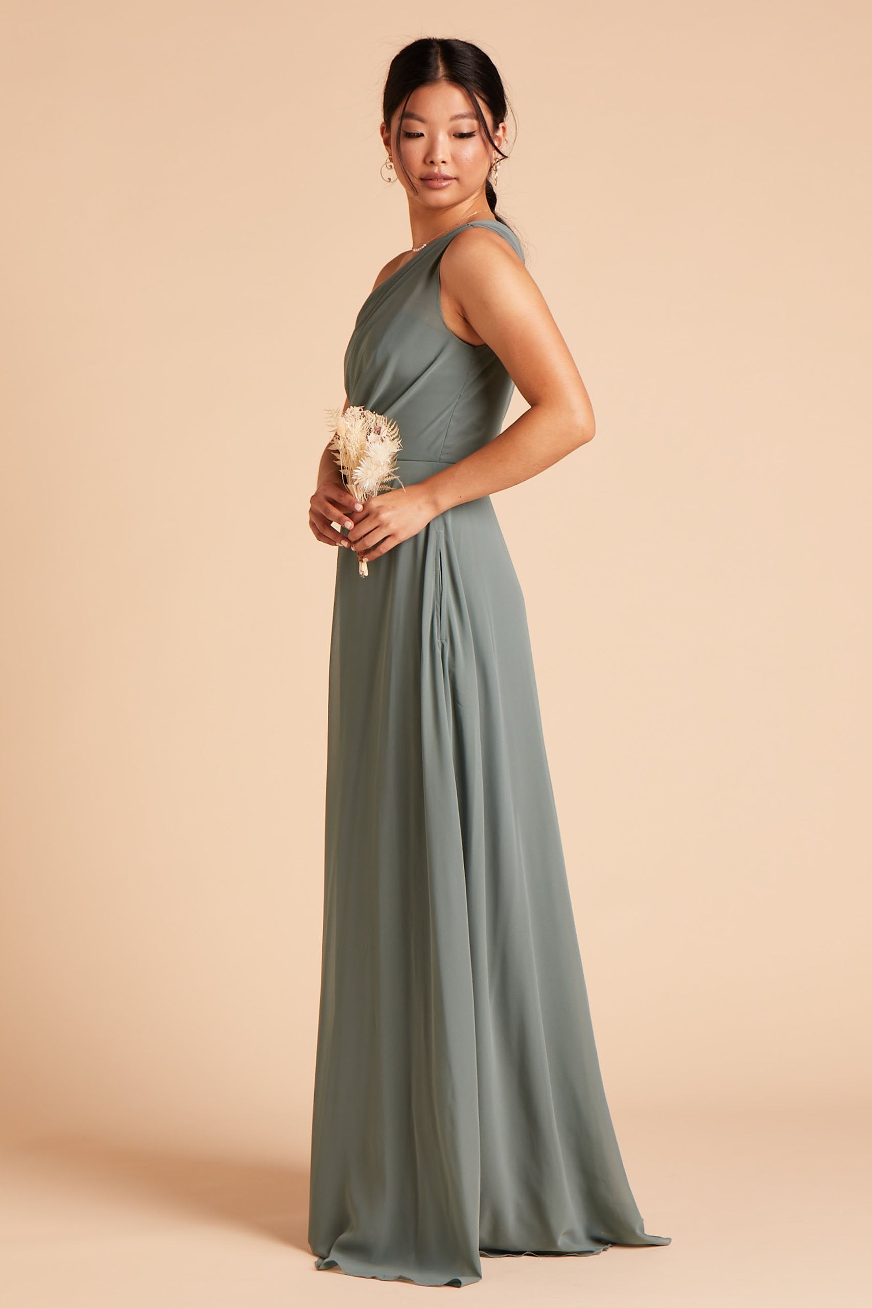 Side view of the Kira Dress in sea glass chiffon without the optional slit shows a model from the side with the inseam pocket showing. 