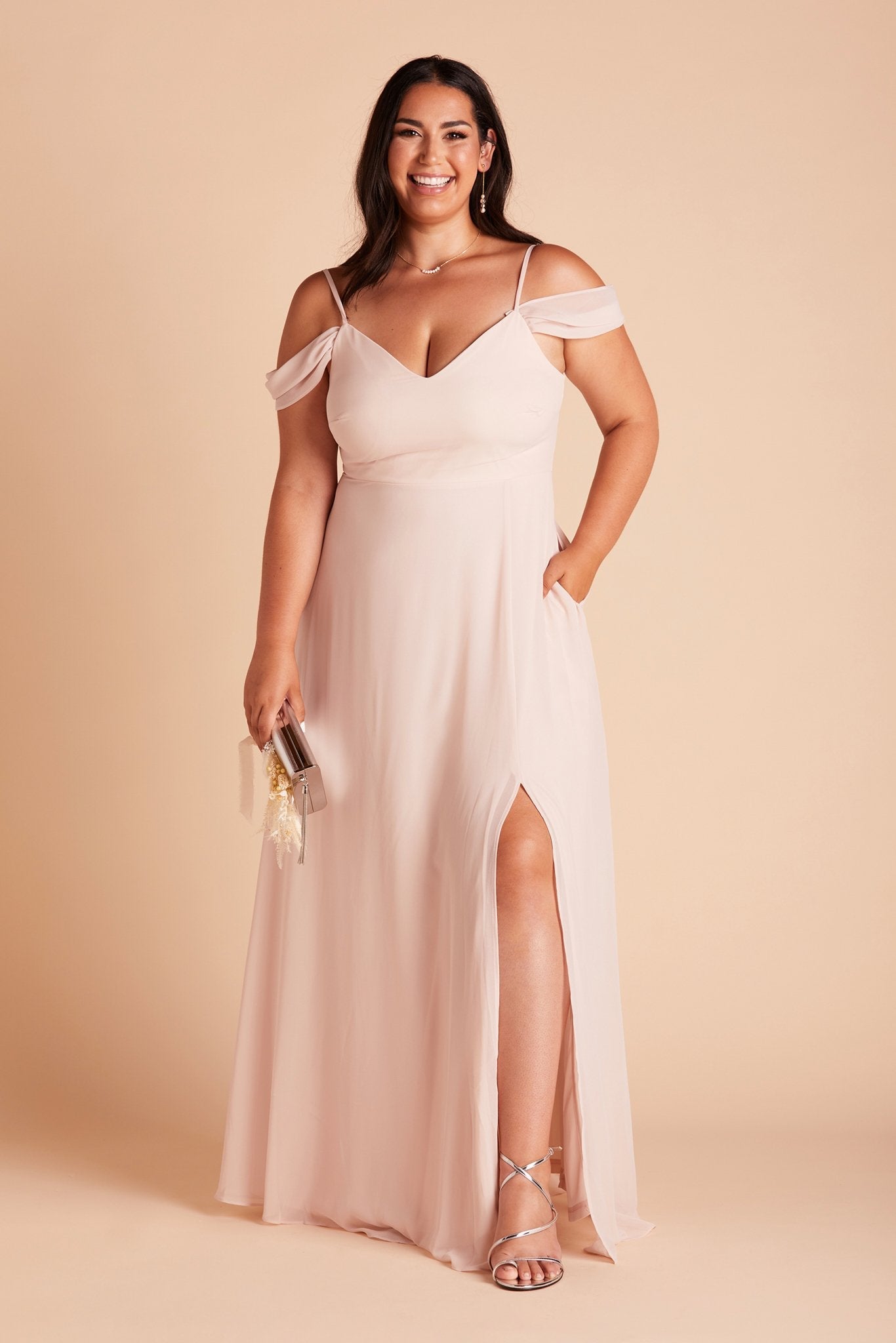 Devin convertible plus size bridesmaids dress with slit in pale blush chiffon by Birdy Grey, front view with hand in pocket