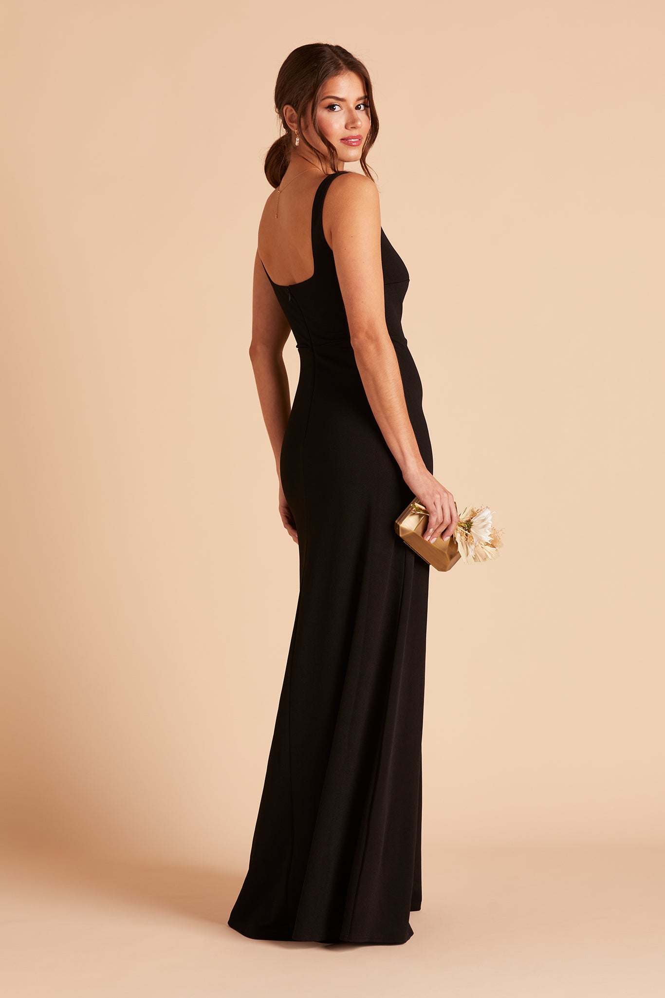 Side view of the Alex Convertible Bridesmaid Dress in black crepe worn without shoulder ties reveals a fitted bust and waistline with a delicate flowing floor-length skirt.