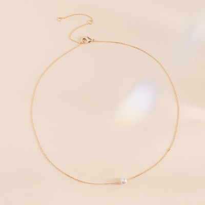 Flat view of the Santa Barbara Single Pearl Necklace shows a gold plated chain necklace with a single pearl. The necklace can be adjusted to three different lengths with an easy to open clasp.