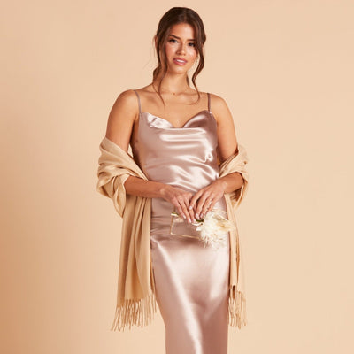 Front view of the Shawl with Fringe in beige shows a model with a slender figure and medium skin wearing the Lisa Satin Midi Dress in taupe with the shawl draped over their shoulders. 