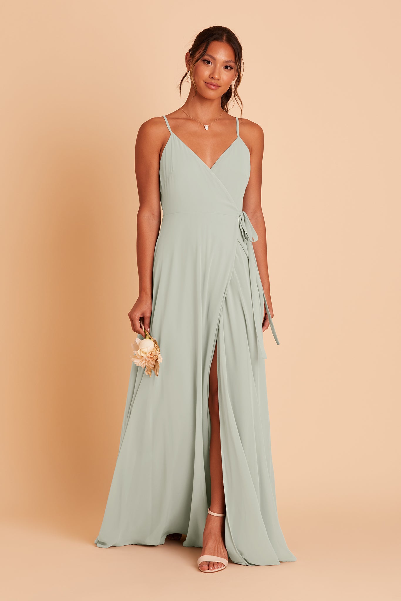 Front view of the floor-length wrap-style Cindy Bridesmaid Dress in sage chiffon by Birdy Grey with a V-neck front. The flowing skirt opens to a center front slit.