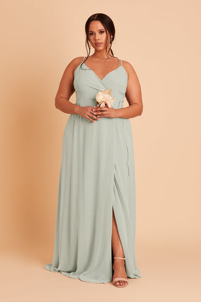 Front view of the floor-length wrap-style Cindy Plus Size Bridesmaid Dress in sage chiffon by Birdy Grey with a V-neck front. The flowing skirt opens to a center front slit.