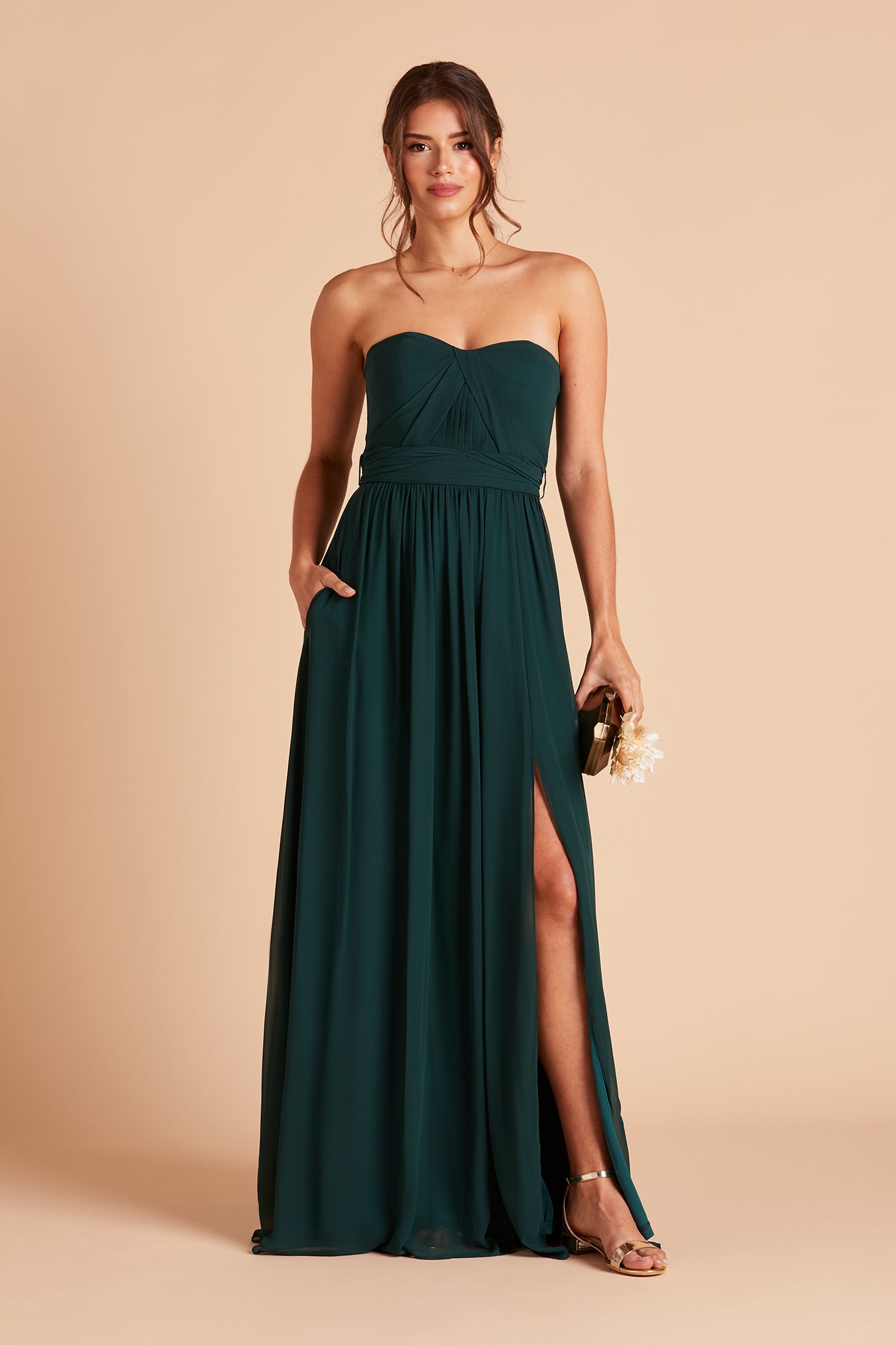 Front view of the floor-length Grace Convertible Dress in emerald chiffon as the model rests her left hand in the hidden side pocket.