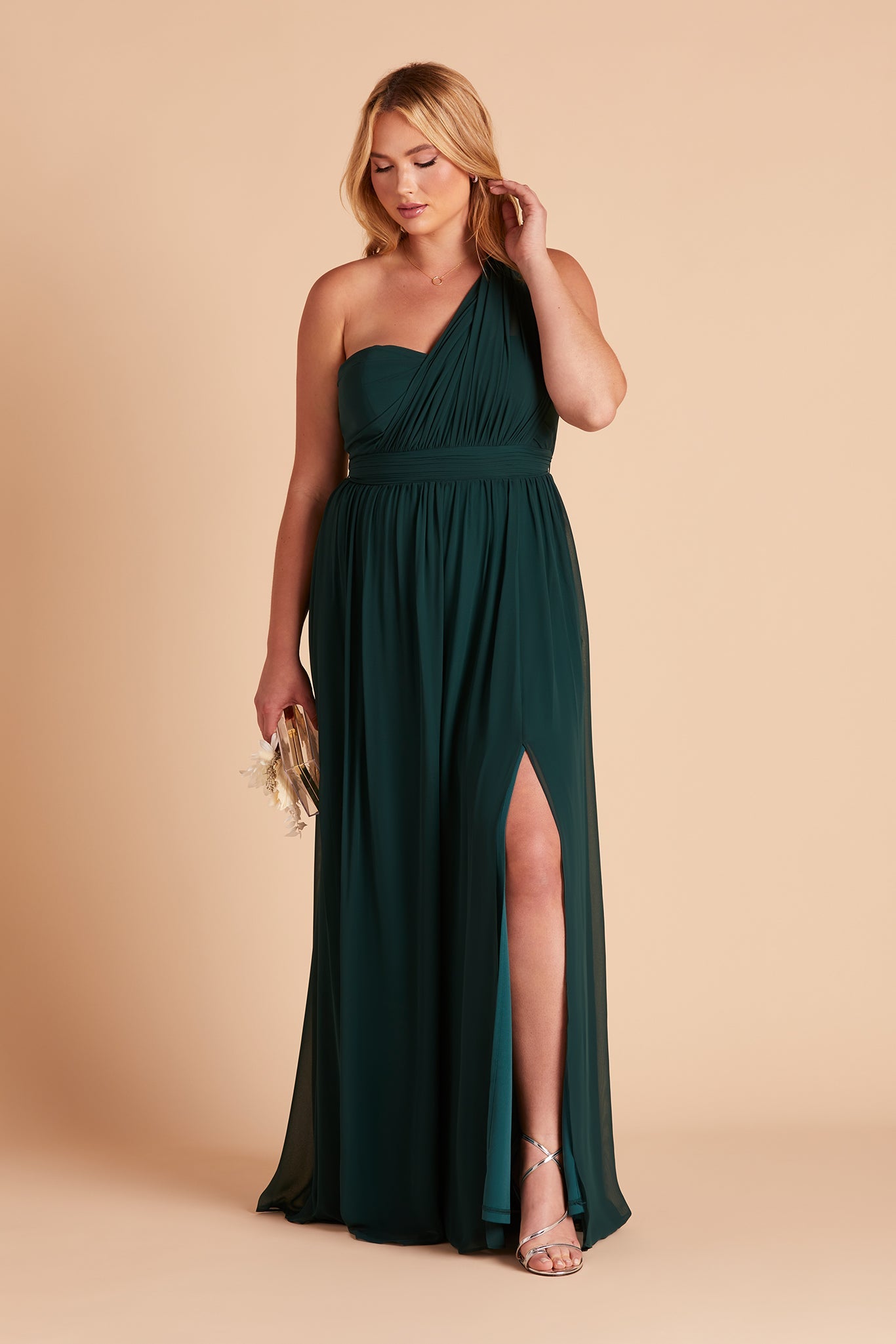 Front view of the floor-length Grace Convertible Plus Size Bridesmaid Dress in emerald chiffon with both streamers pulled over the left shoulder on a curvy model with light skin tone.