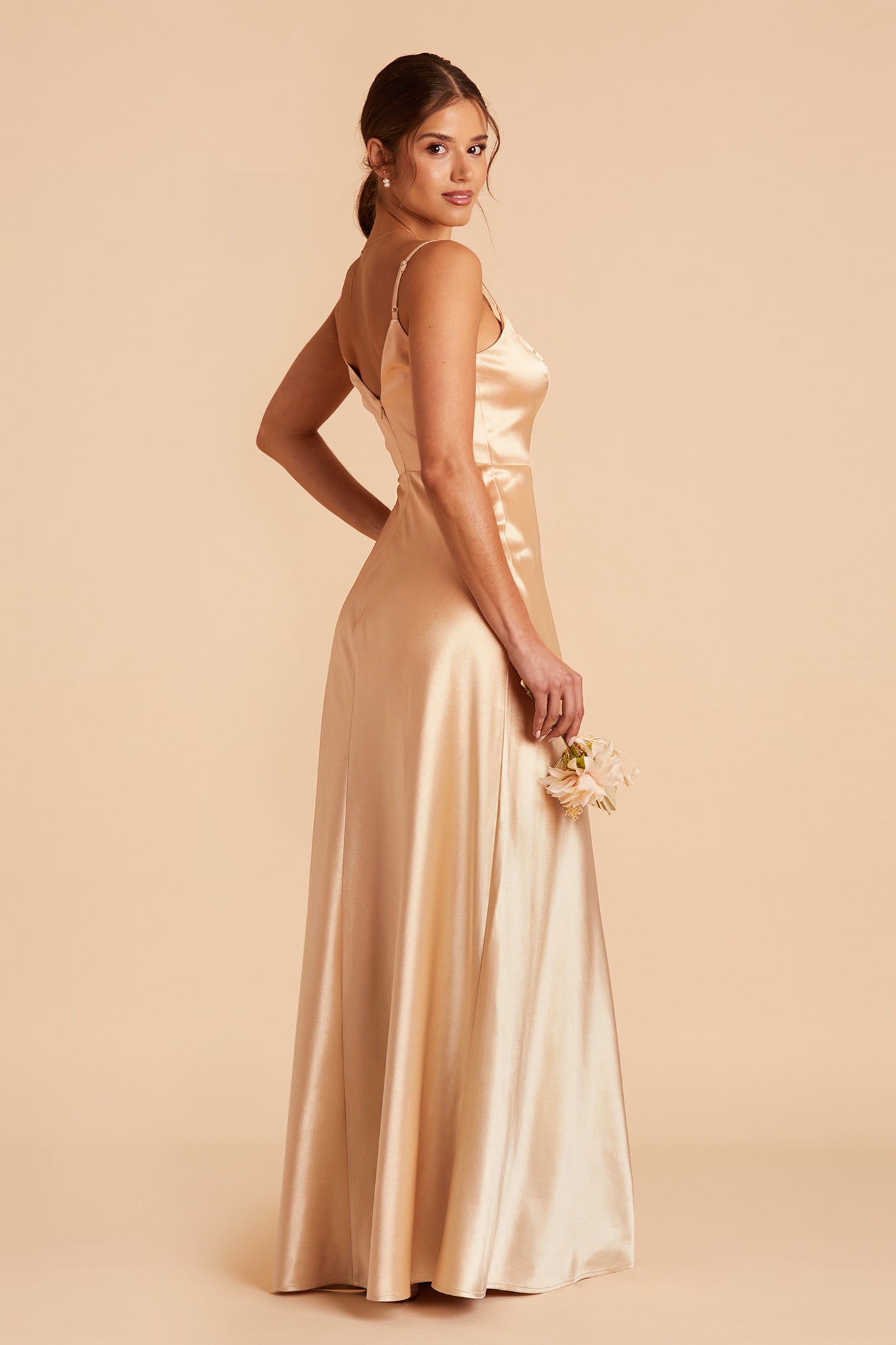 Side view of the Jay Bridesmaid Dress in gold satin reveals a V-shaped back with a full skirt flowing from a fitted top.