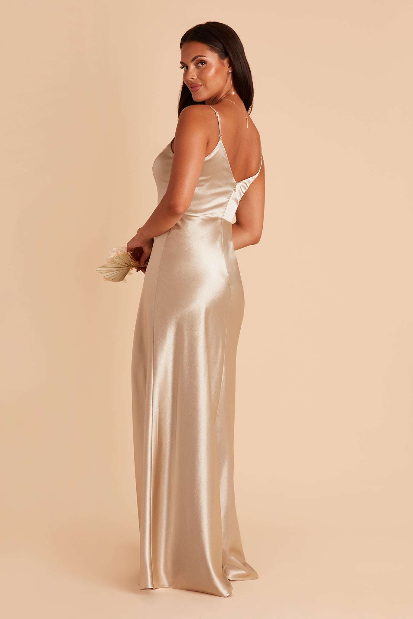 Side view of the Jay Bridesmaid Dress in neutral champagne satin reveals a V-shaped back with a full skirt flowing from a fitted top.