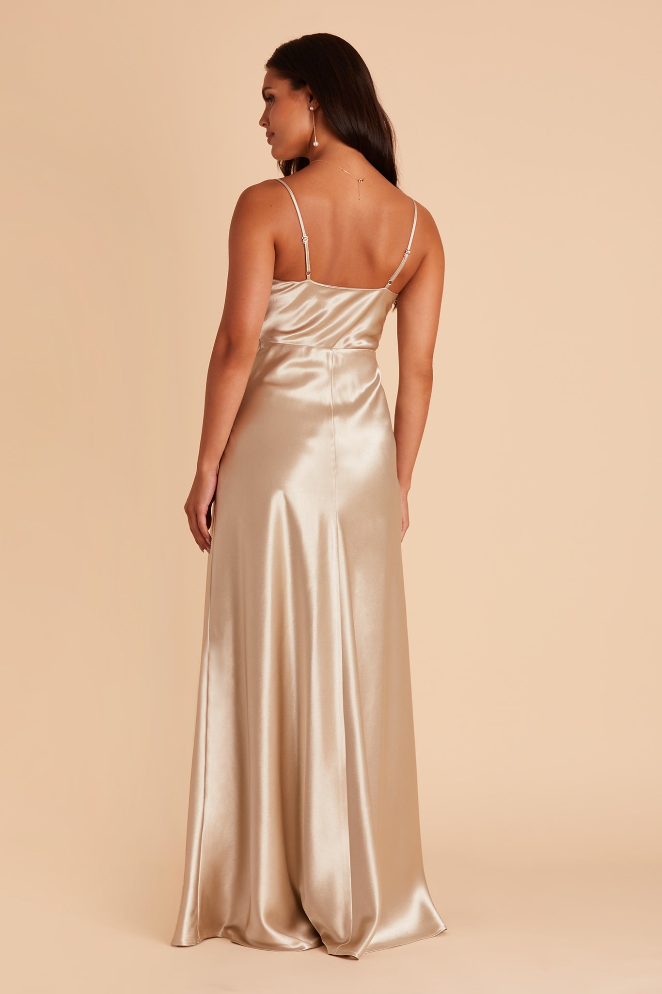 Back view of the Lisa Long Dress in neutral champagne satin shows the back of the dress with adjustable spaghetti straps and a smooth fit in the bodice and waist that attach to a full-length skirt.  