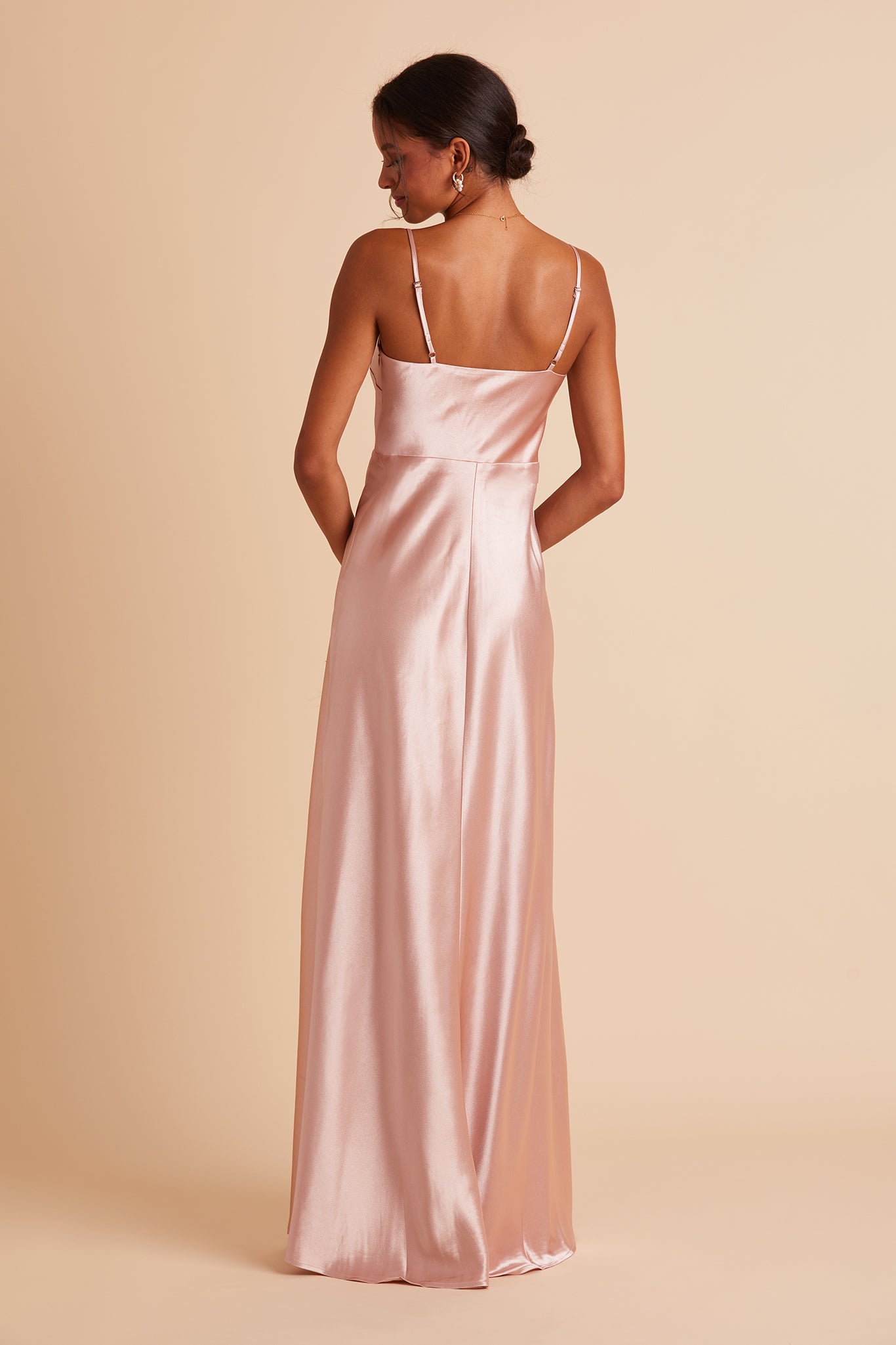 Back view of the Lisa Long Dress in rose gold satin shows the back of the dress with adjustable spaghetti straps and a smooth fit in the bodice and waist that attach to a full length skirt.  