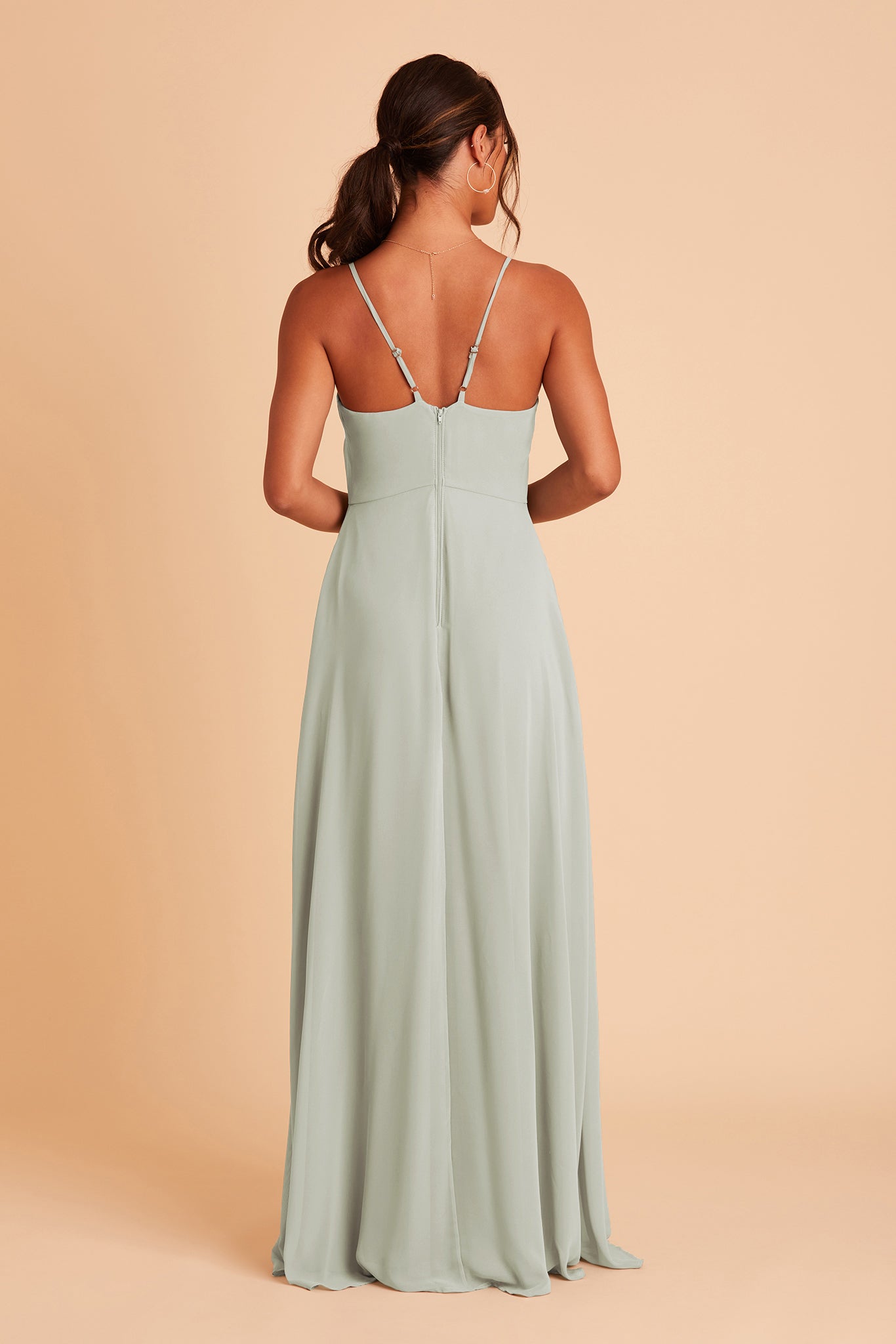 Back view of the Theresa Dress in sage chiffon with the optional slit shows the adjustable, angled shoulder straps attached at the bodice center seam. The hidden zipper is shown in the bodice and skirt center seam. 