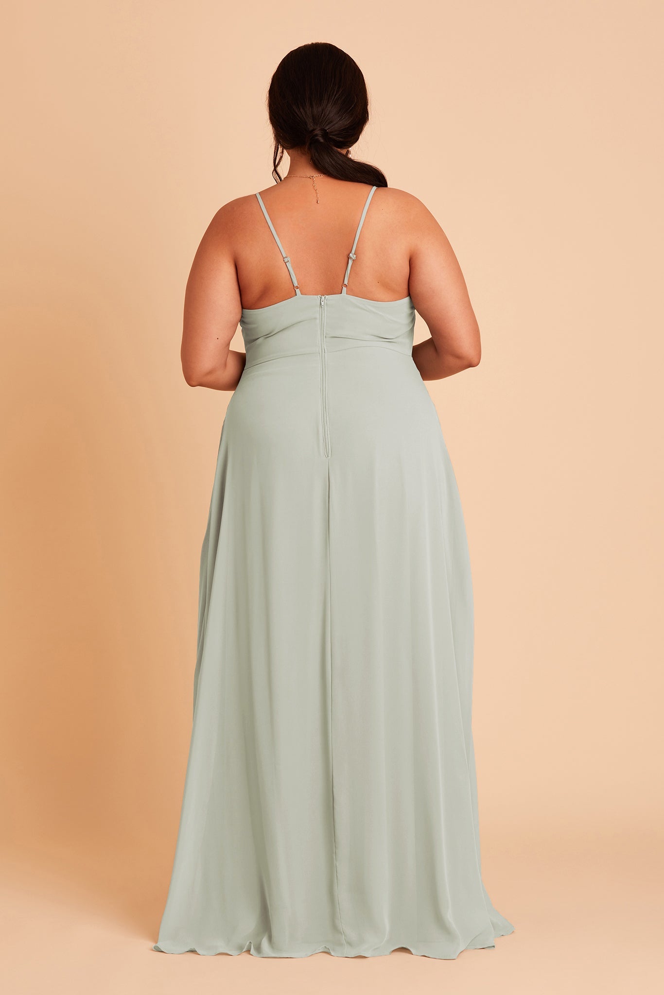 Back view of the Theresa Dress Curve in sage chiffon with the optional slit shows the adjustable, angled shoulder straps attached at the bodice center seam. The hidden zipper is shown in the bodice and skirt center seam. 