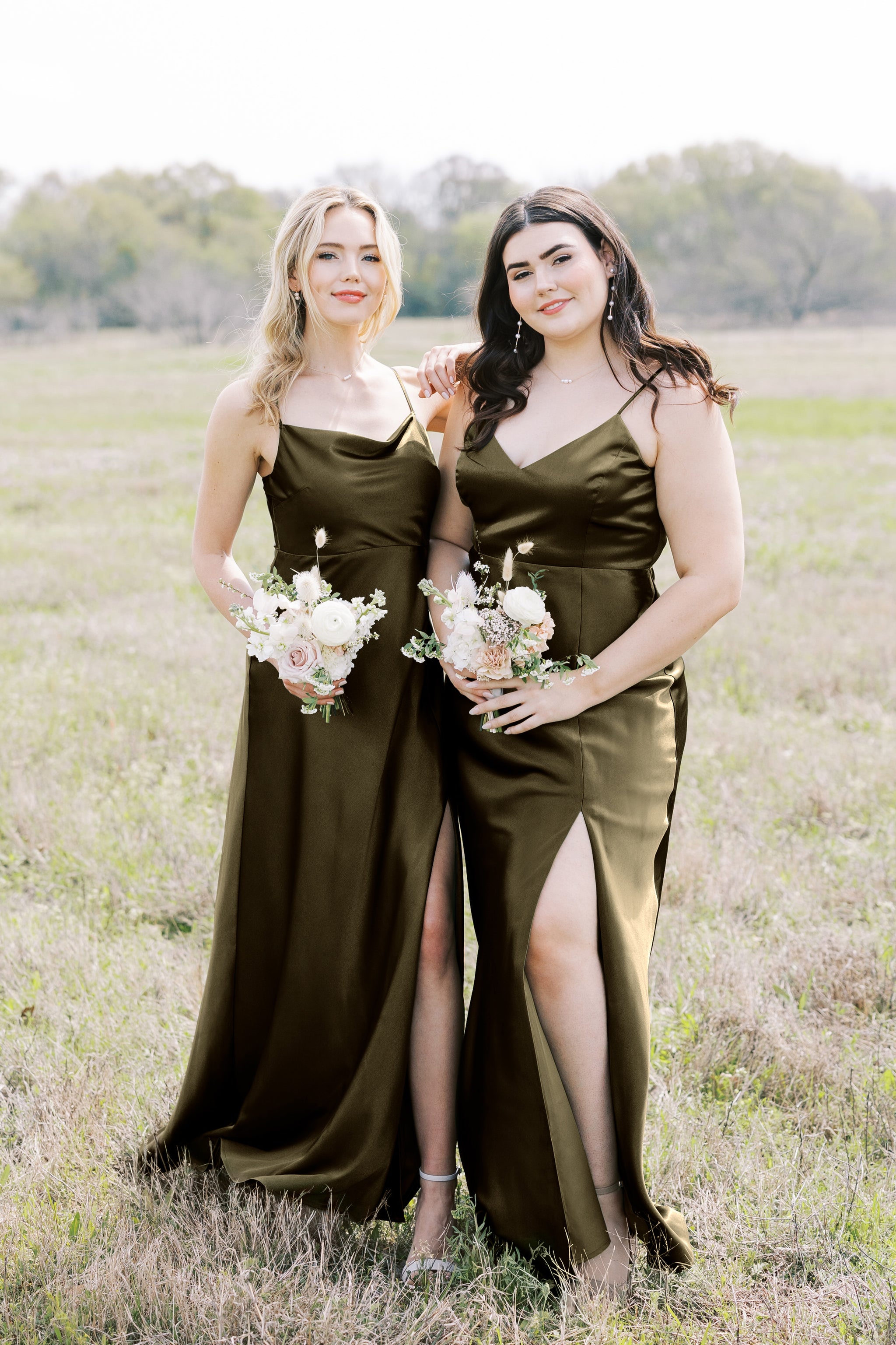 Front view of two models wearing coordinating floor length dresses in olive satin. The Lisa Long dress is worn by slender model with a light skin tone. The Jay Curve dress is worn by a full figured model with a light skin tone. 