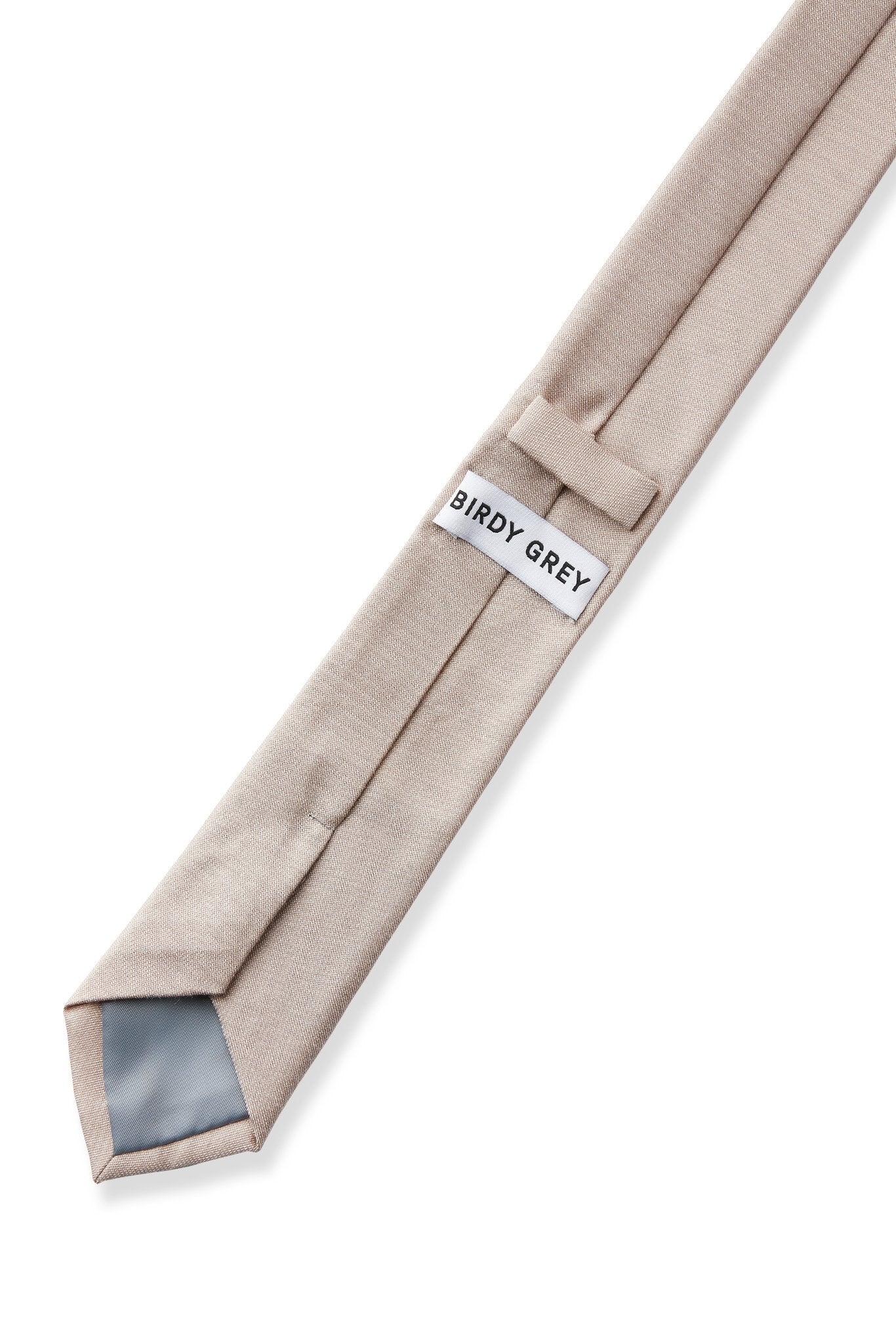 Elevated back view of the Simon Necktie in taupe fully extended on a white background showing necktie satin lining in grey, a keeper loop to tuck the necktie end, and a label that reads, 