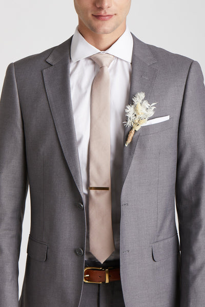 Front closeup view of the model wearing the Simon Necktie in taupe with a white button down collared shirt and medium grey suit. The tie is kept in place with a narrow rectangular tie clasp in matte gold.