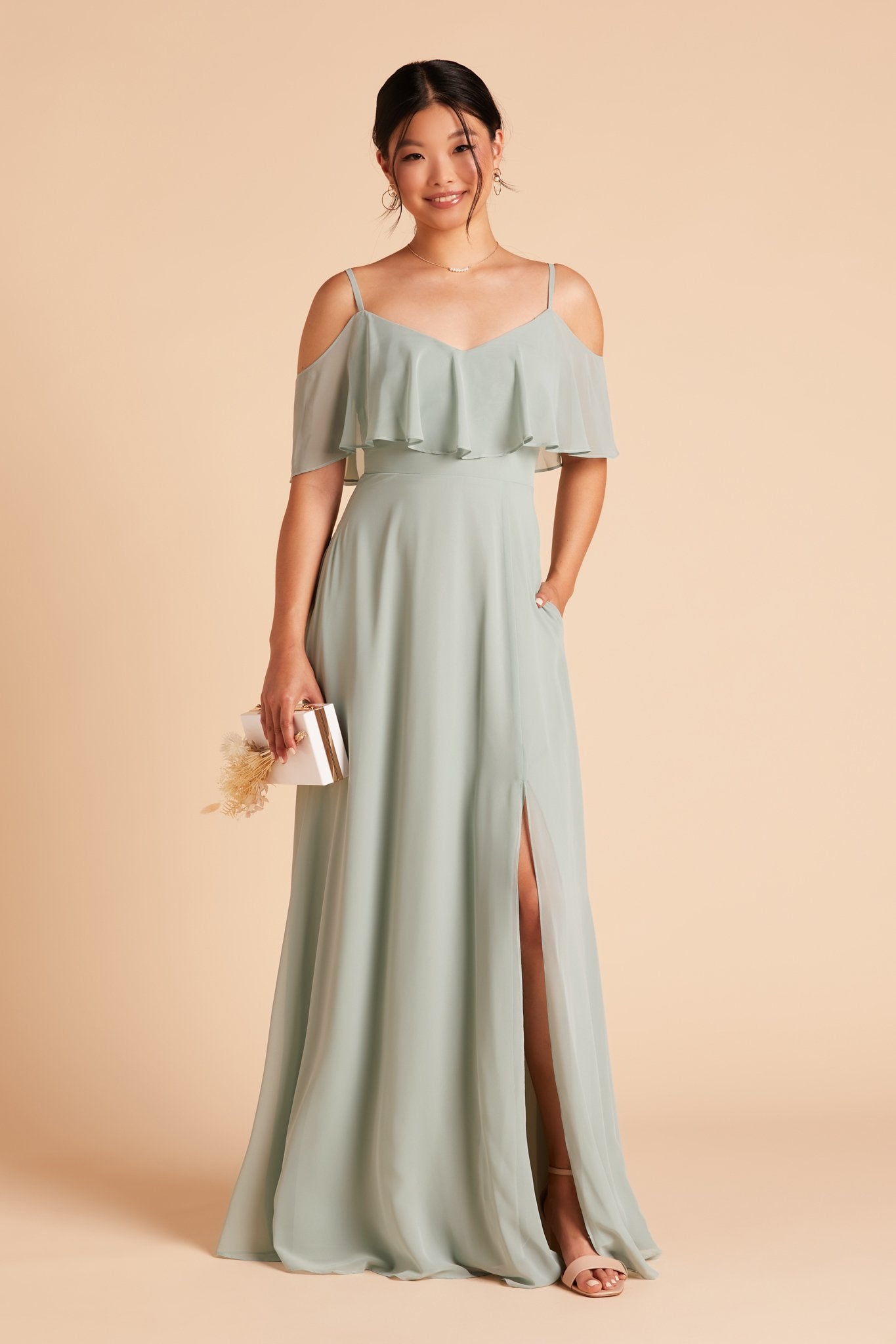 Jane convertible bridesmaid dress with slit in sage green chiffon by Birdy Grey, front view with hand in pocket 