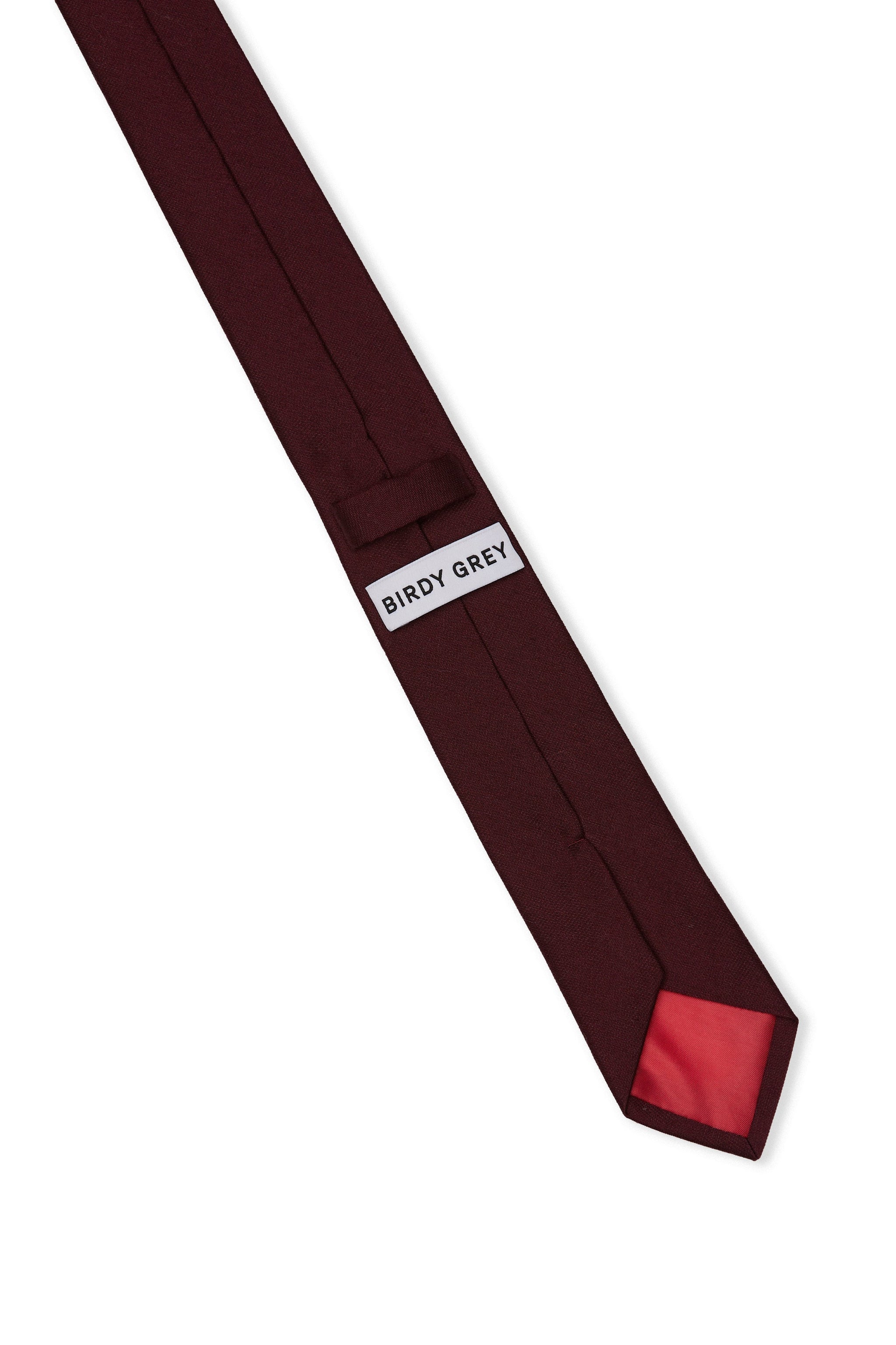 Elevated back view of the Simon Necktie in cabernet fully extended on a white background showing the necktie satin lining in cabernet, a keeper loop to tuck the necktie end, and a label that reads, 