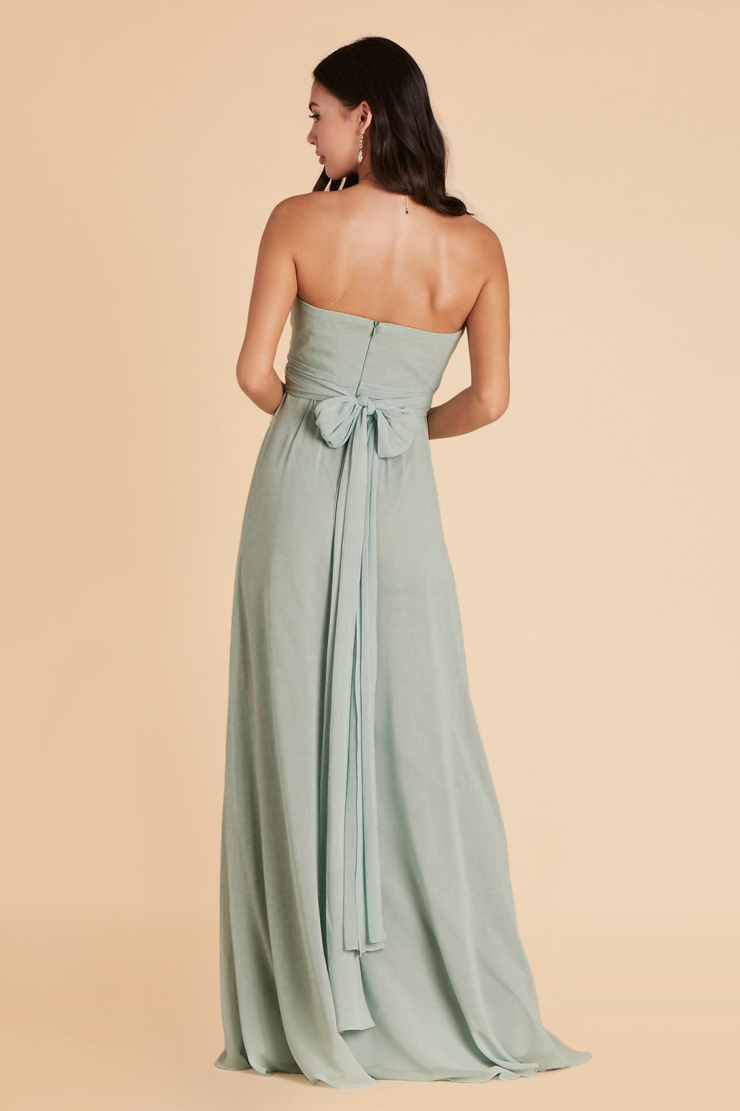 Back view of the Grace Convertible Bridesmaid Dress in sage chiffon reveals an open back cut below the shoulder blades with front streamers tied around the waist in a delicate and flowing bow.