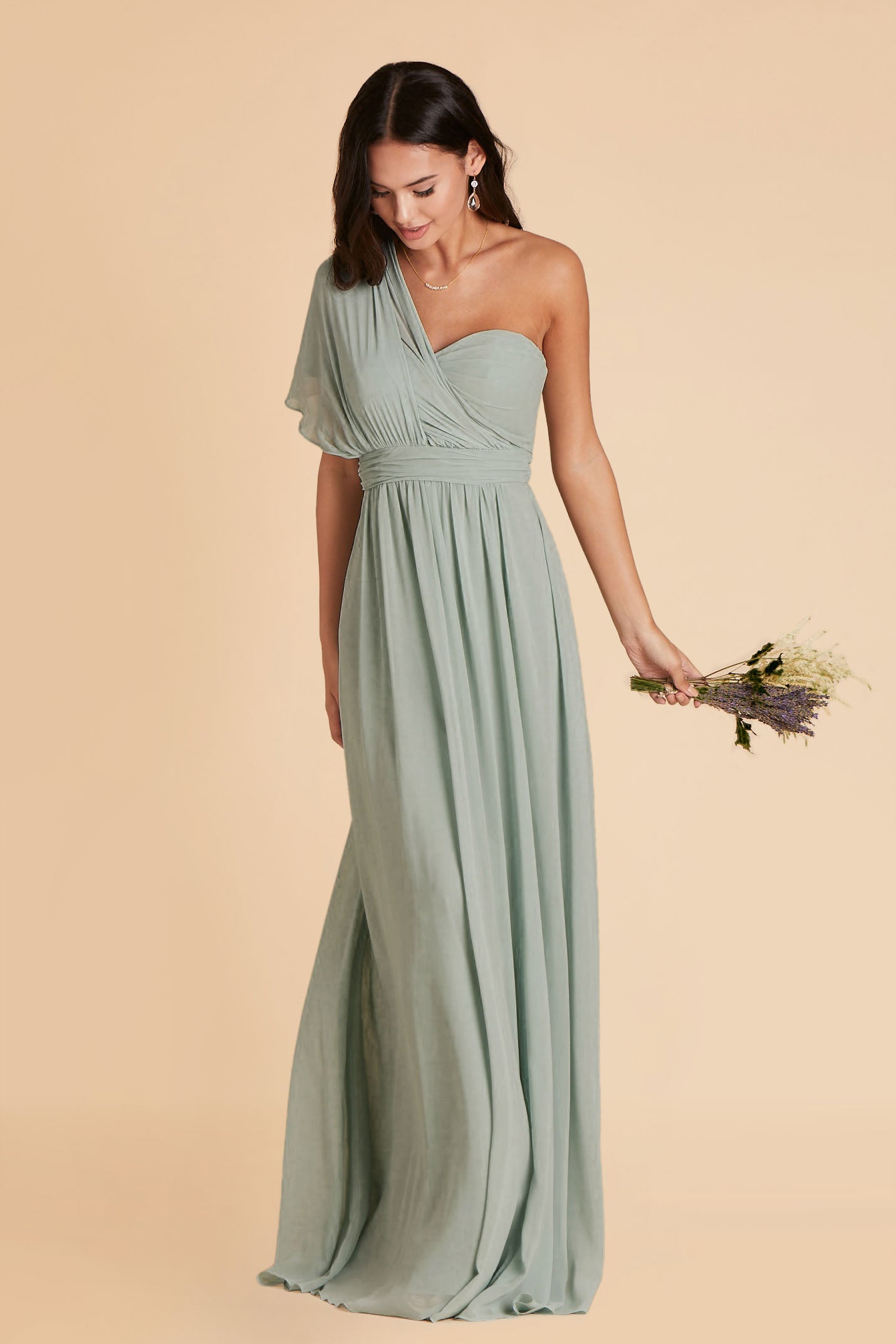 Front view of the Grace Convertible Dress in sage chiffon worn by a slender model with a medium skin tone. Front streamers are pulled over the right shoulder and fanned out wide, draping over the shoulder for an elegant asymmetrical look