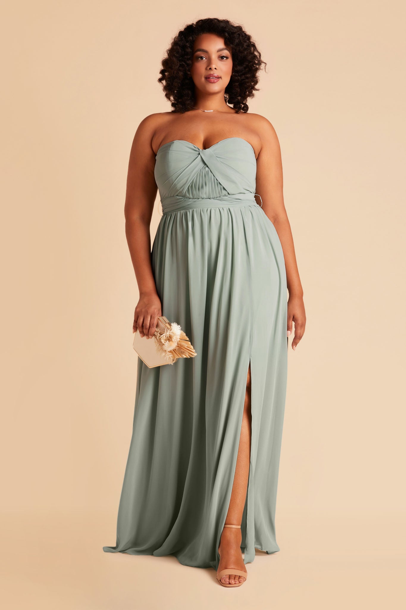 Front view of the Grace Convertible Plus Size Bridesmaid Dress in sage chiffon by Birdy Grey features a sweetheart neckline and a slit in the flowing floor-length skirt over the left leg.