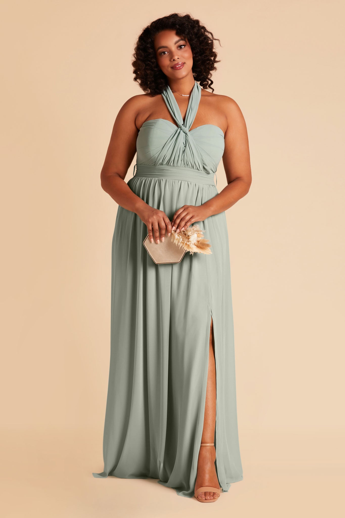 Front view of the Grace Convertible Plus Size Bridesmaid Dress in sage chiffon worn by a curvy model with medium-tone skin.