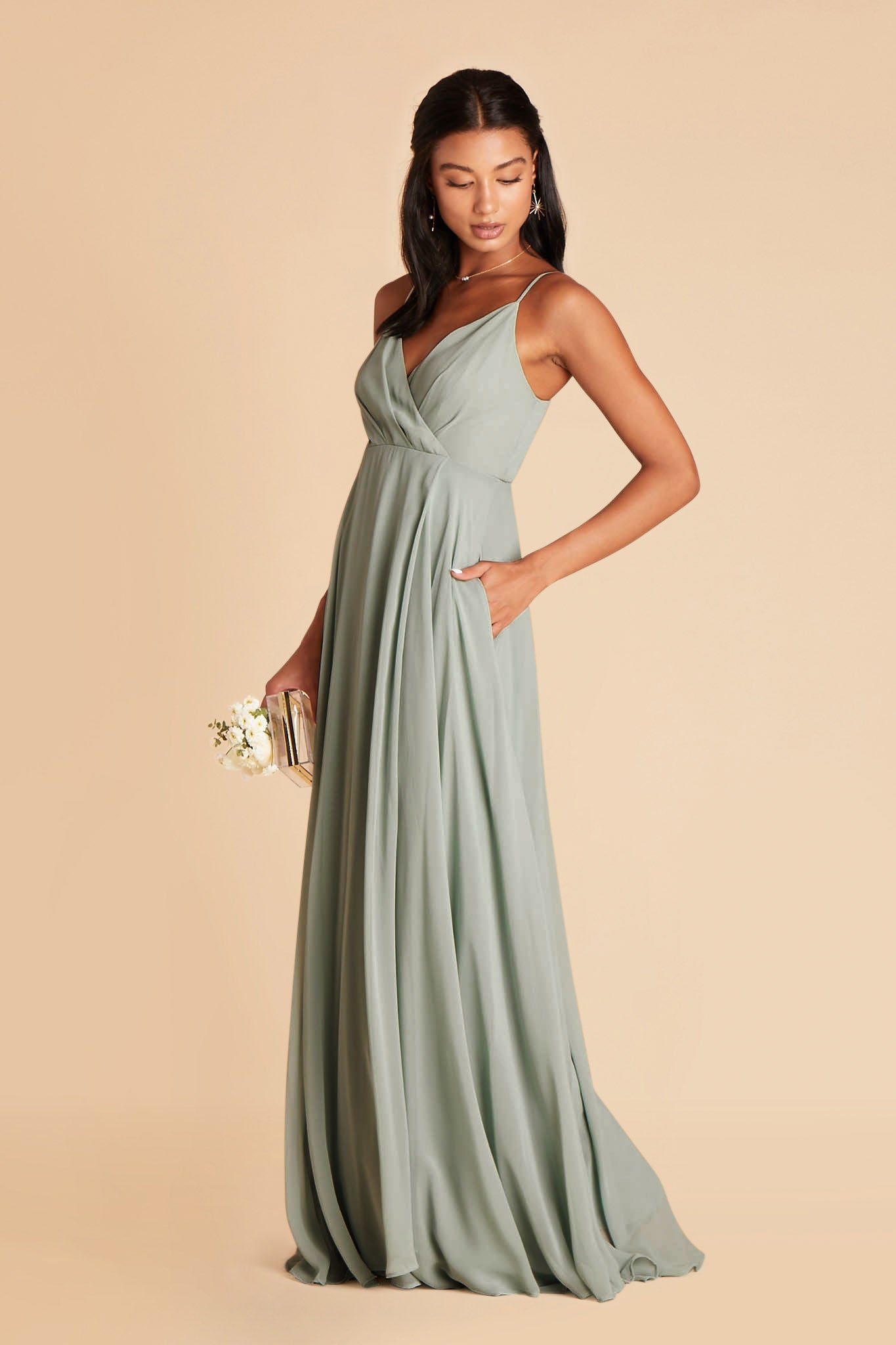 Side view of the Kaia Dress in sage chiffon shows the model with their hand in the side seam pocket.