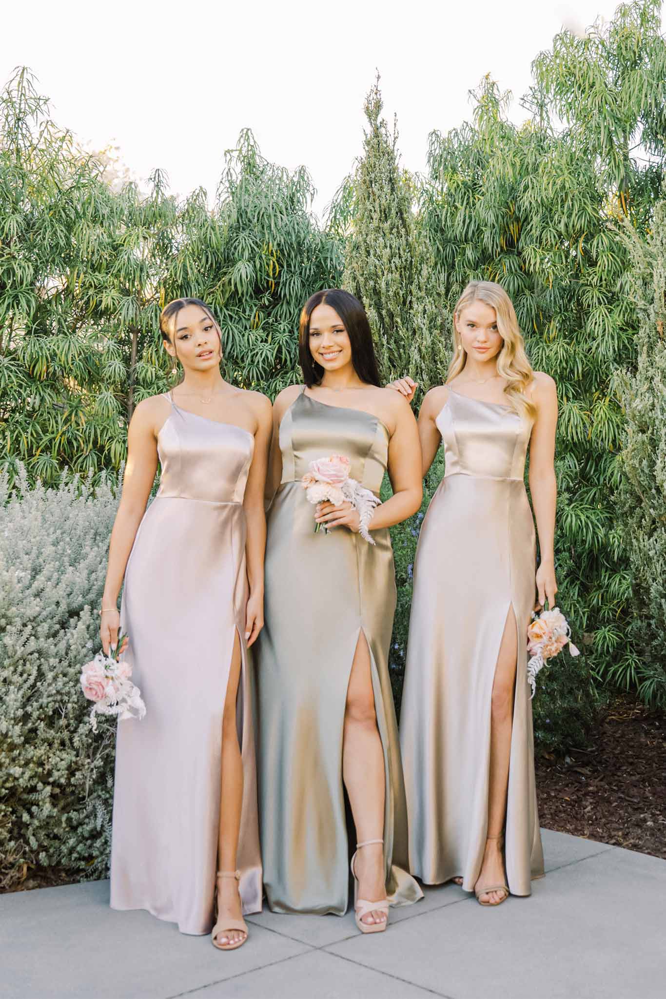 Three one-shoulder neckline bridesmaid dresses in medium green, light taupe, champagne satin